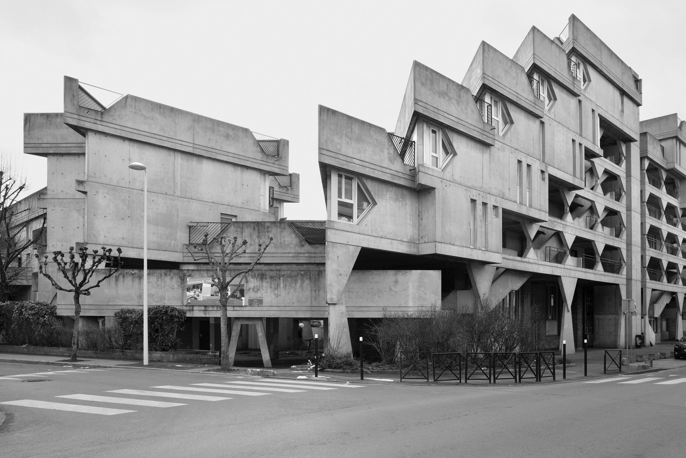 Black and white photo of an angular concrete brutalist building with a stepped roof