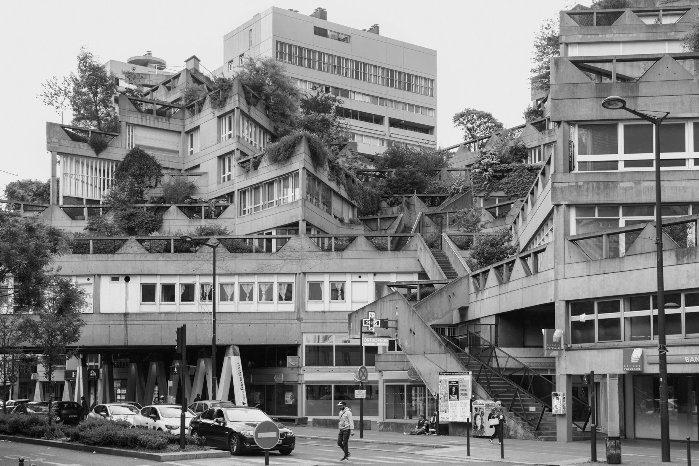 Black and white photo of a brutalist residential and commercial building complex with blocks aligned at different angles