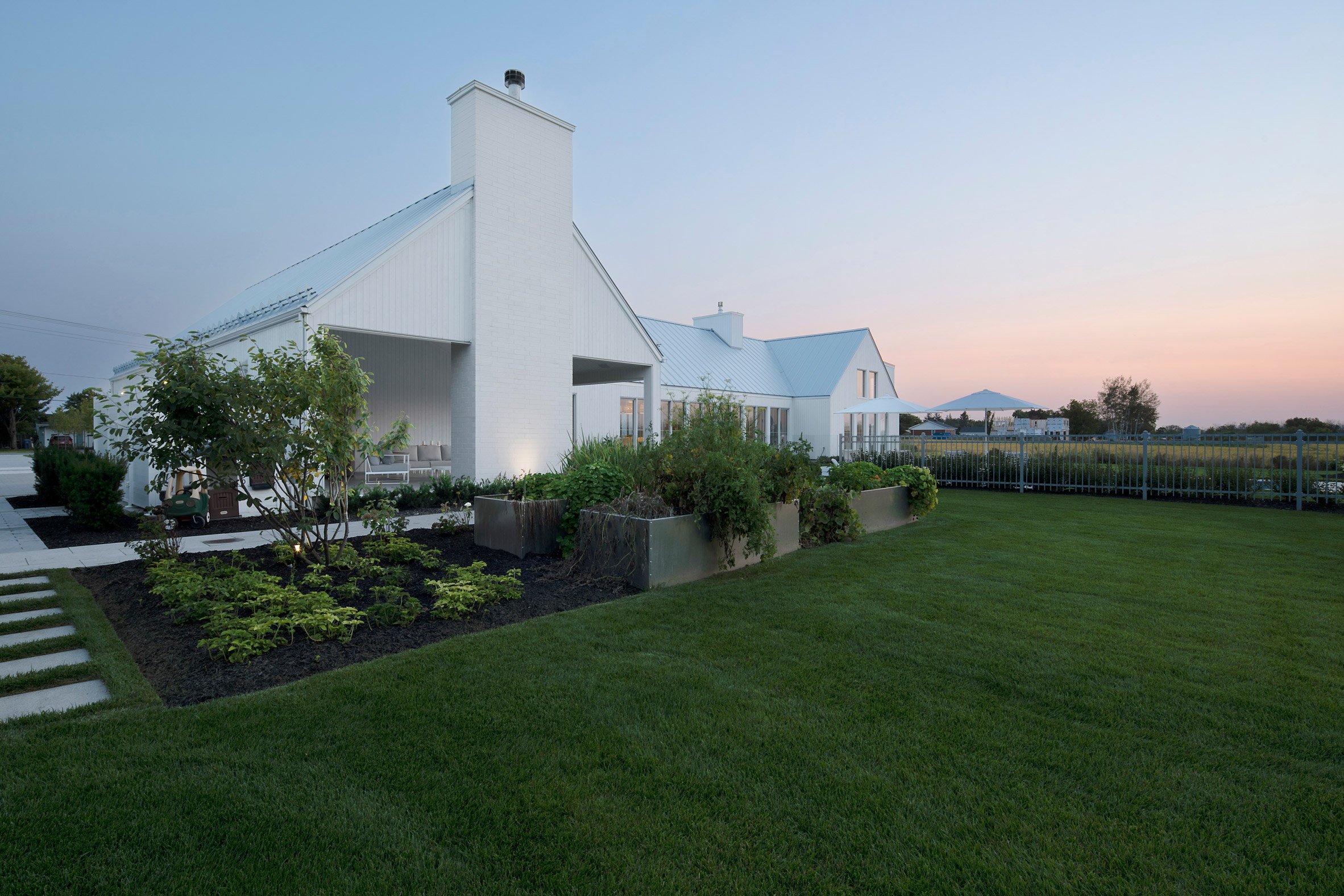 A white U-shaped house with a pitched roof on a green lawn