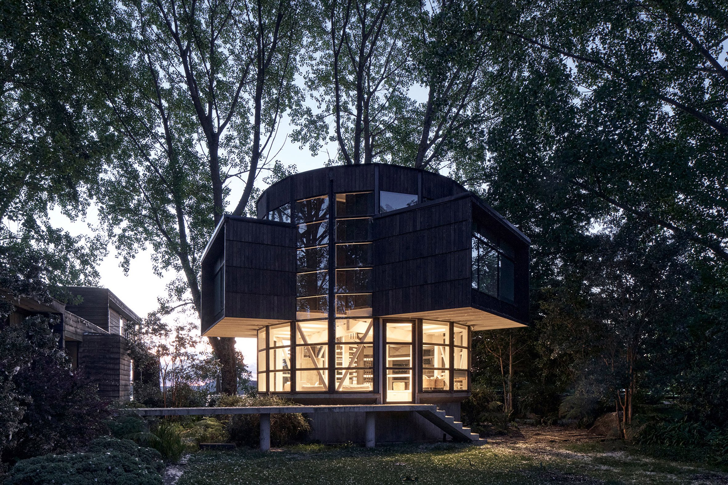 Illuminated house that looks like a lantern in lakeside forest in Chile