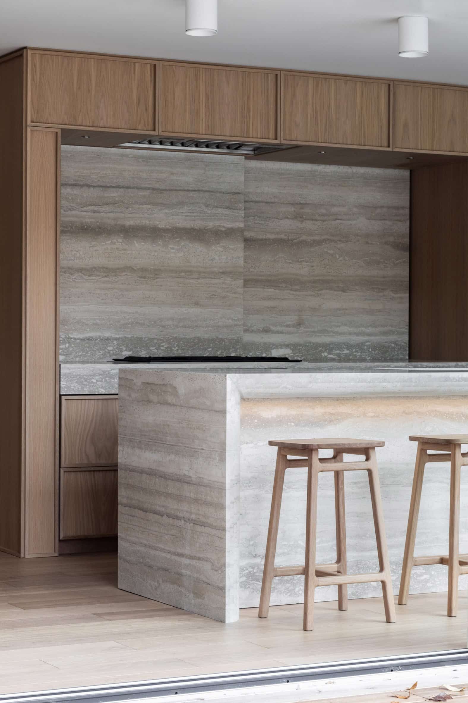 Storage hidden behind slab of travertine backsplash