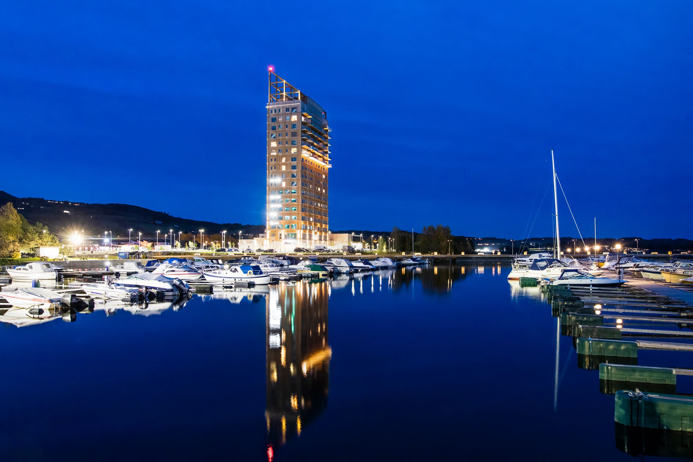 A tall mass-timber building beside a lake