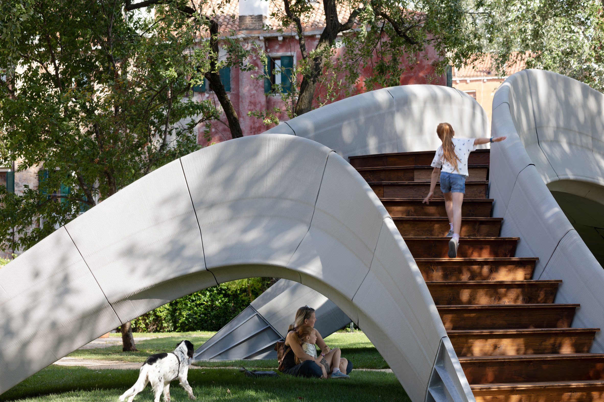 Girl climbing up stairs of Striatus 3D-printed concrete footbridge
