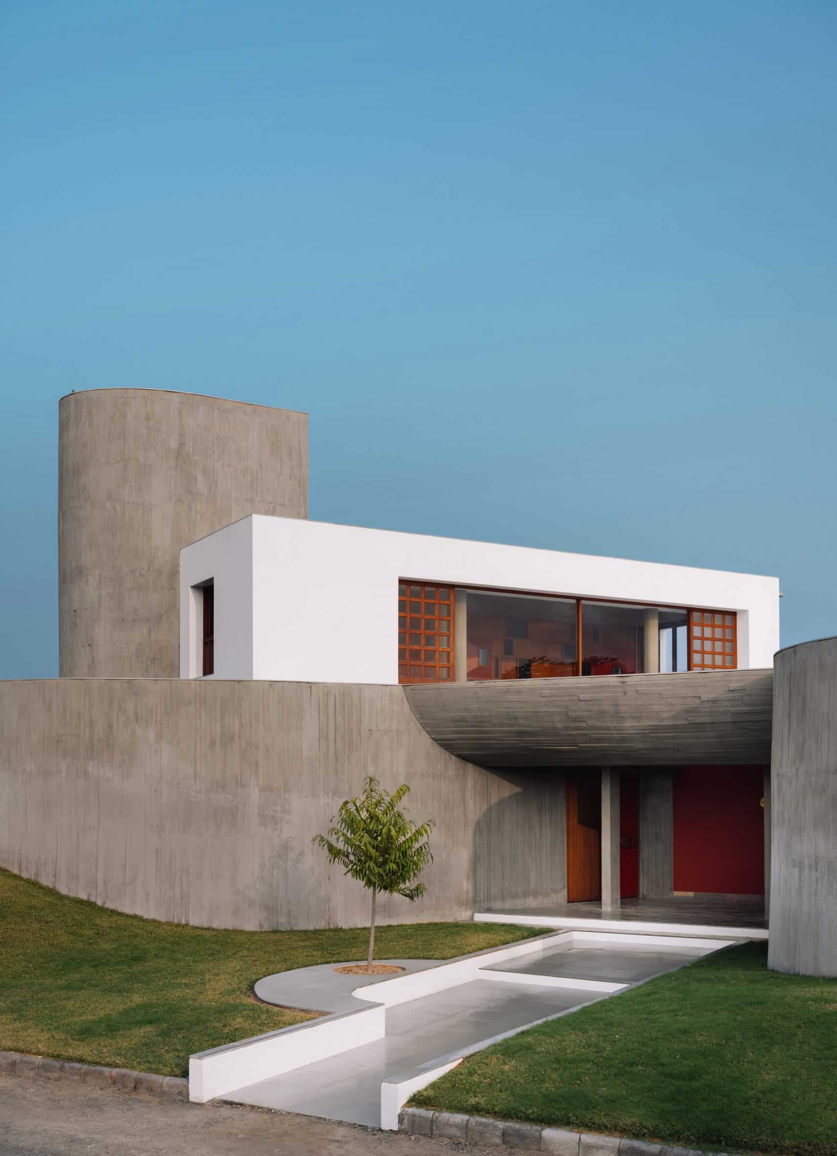 Entrance to the concrete Enclosure house by Design Ni Dukan with concrete canopy and grass lawn