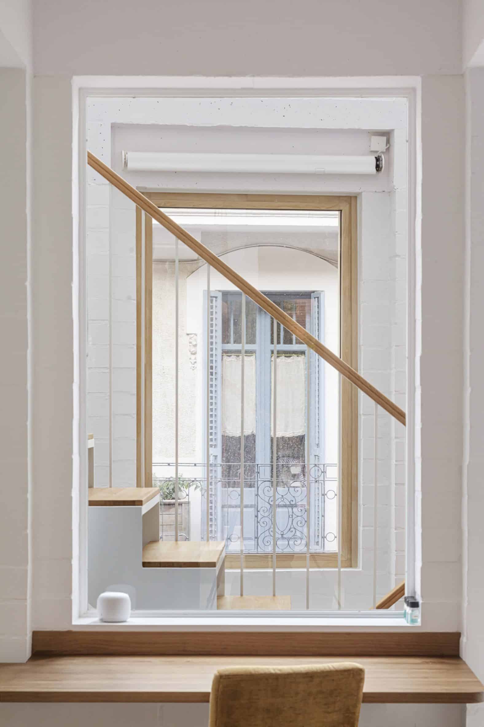 White interior of House 1616 with a square opening revealing a staircase and a window beyond