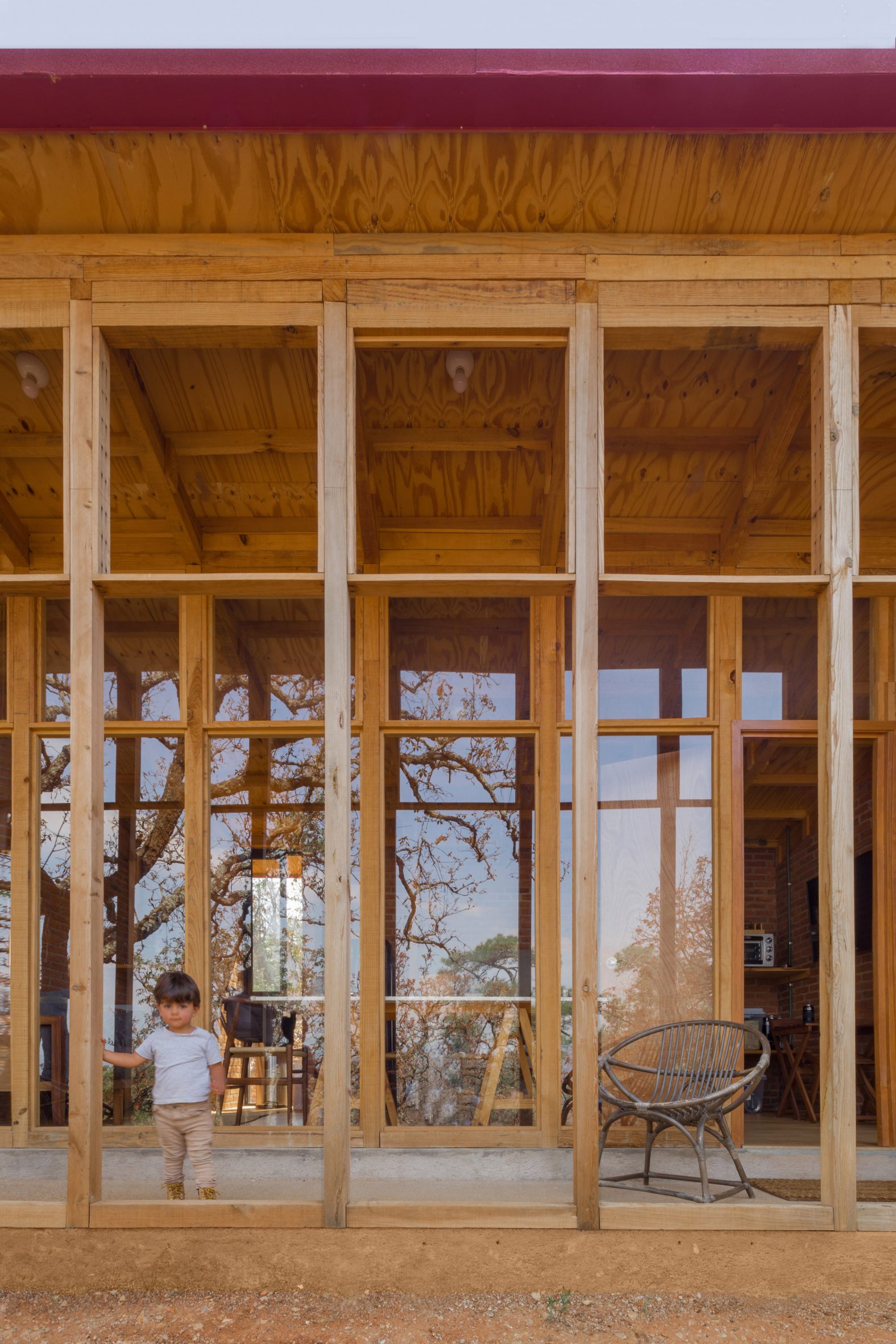 Child playing on a porch with a wooden structure in front of a one-storey home