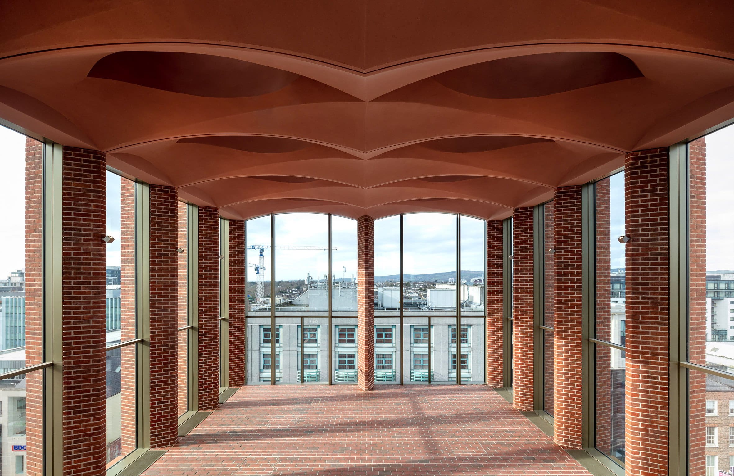 Top floor exhibition space at the International Rugby Experience building by Niall McLaughlin Architects with large windows and arched ceiling