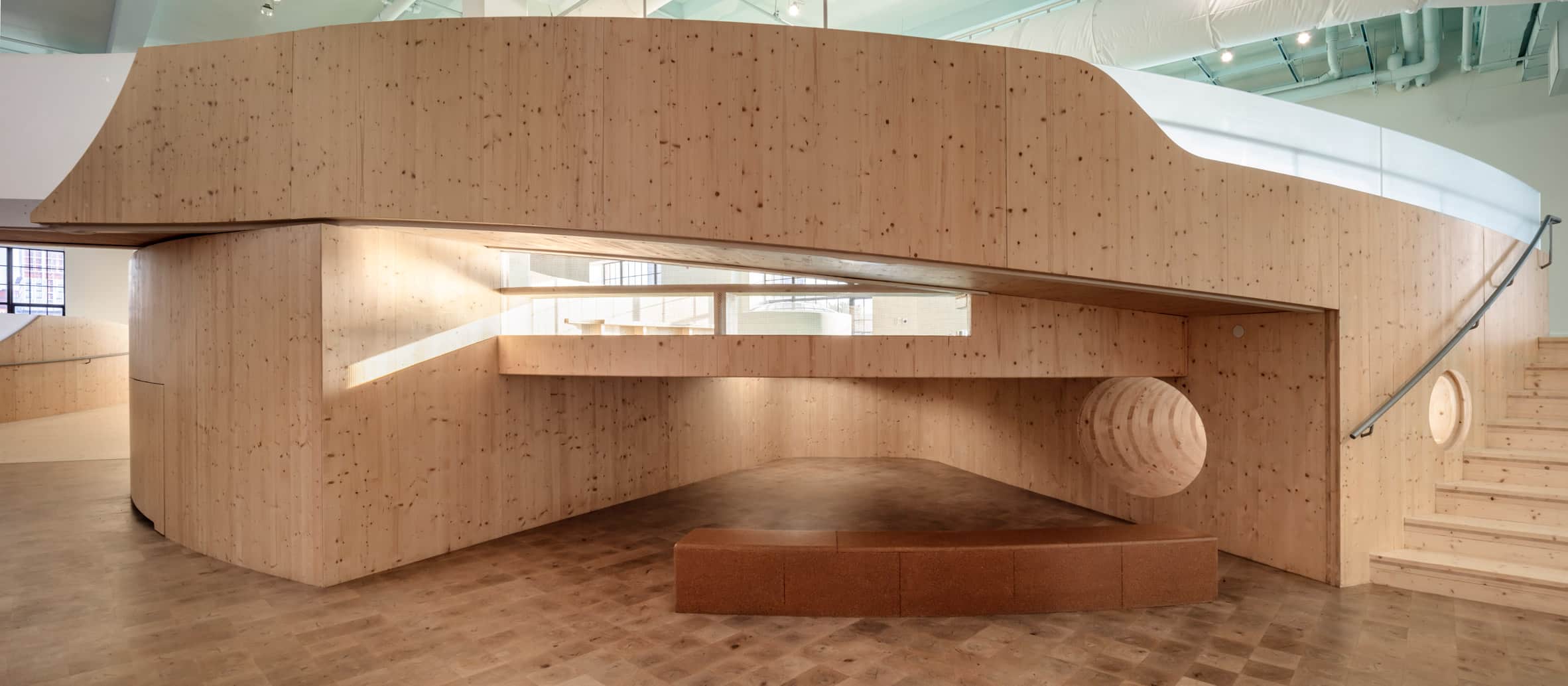 Museum interior with wood flooring and a ramped curving wood walkway
