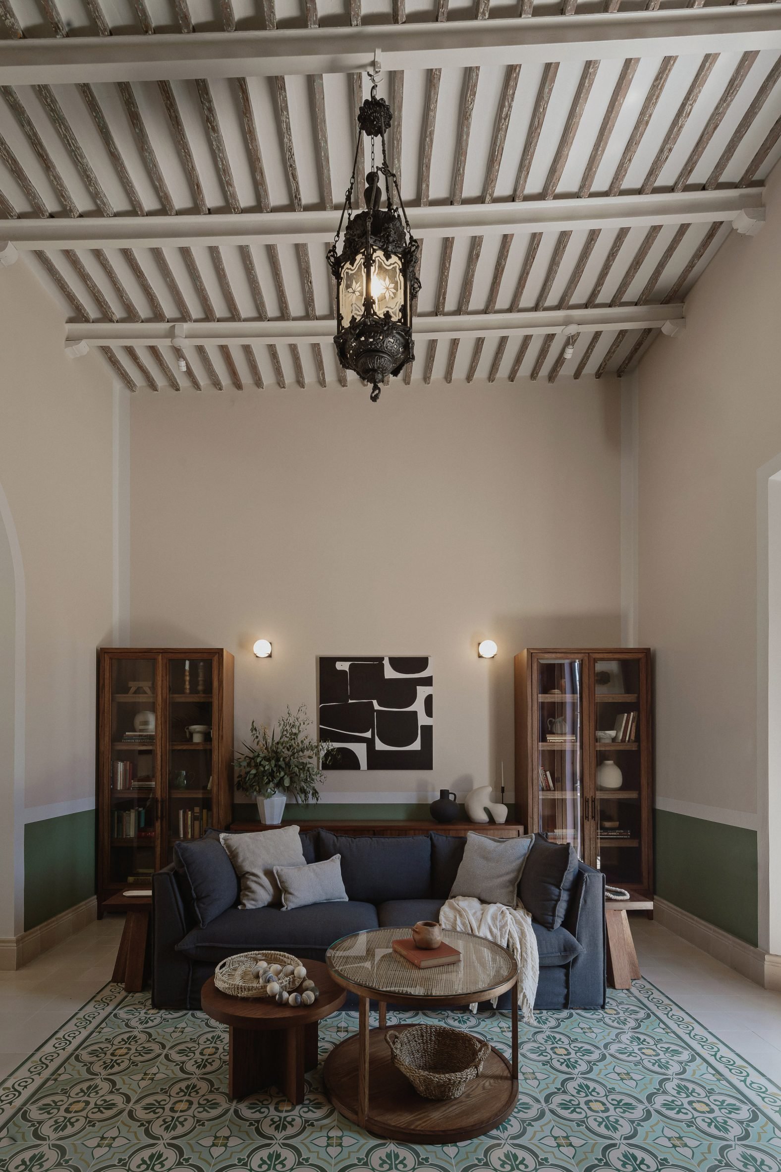 Interior of a living room with mosaic floor tiles, exposed ceiling joists and a blue sofa