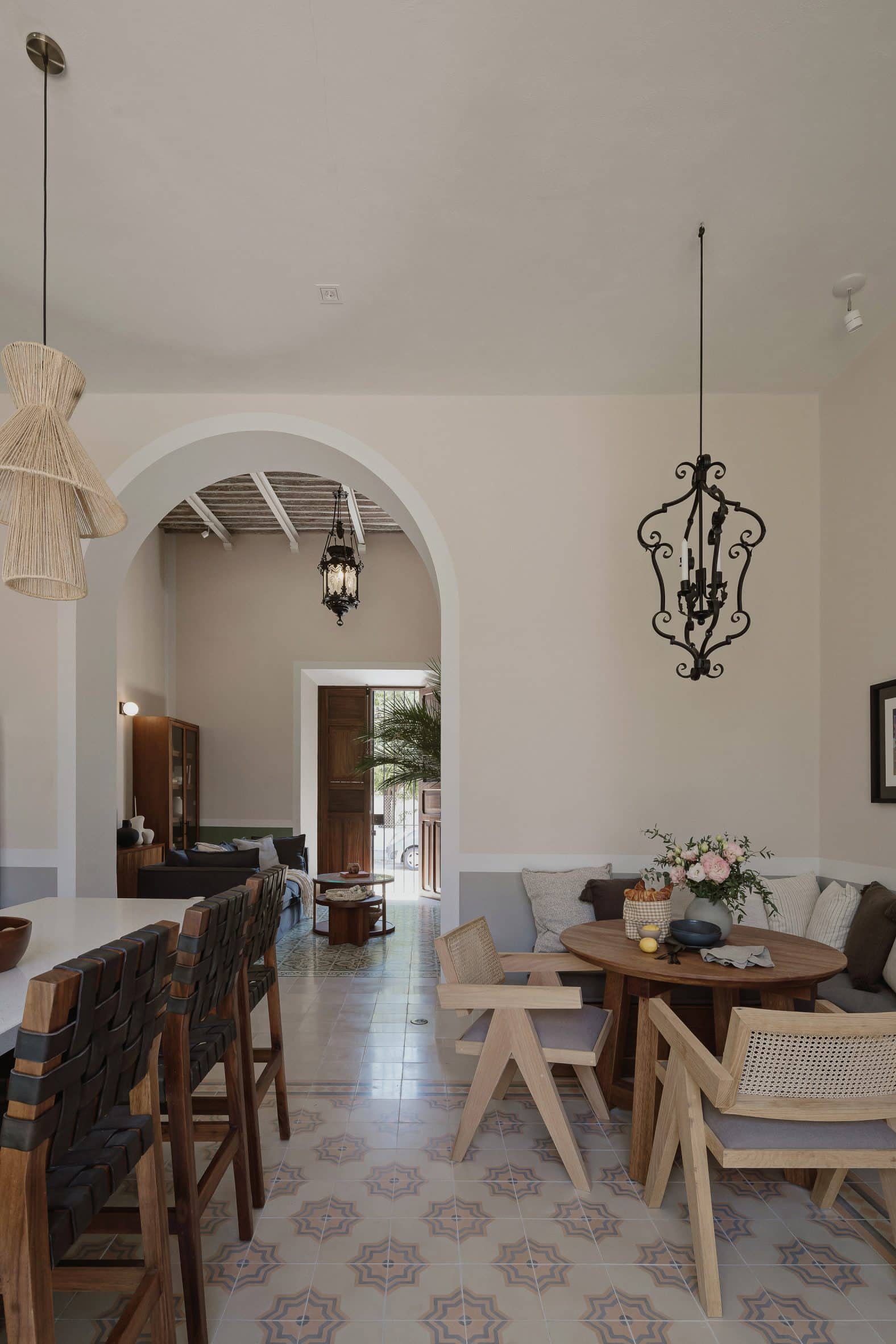 Interior of a kitchen with mosaic floor tiles, a corner breakfast area and archway leading to a living room