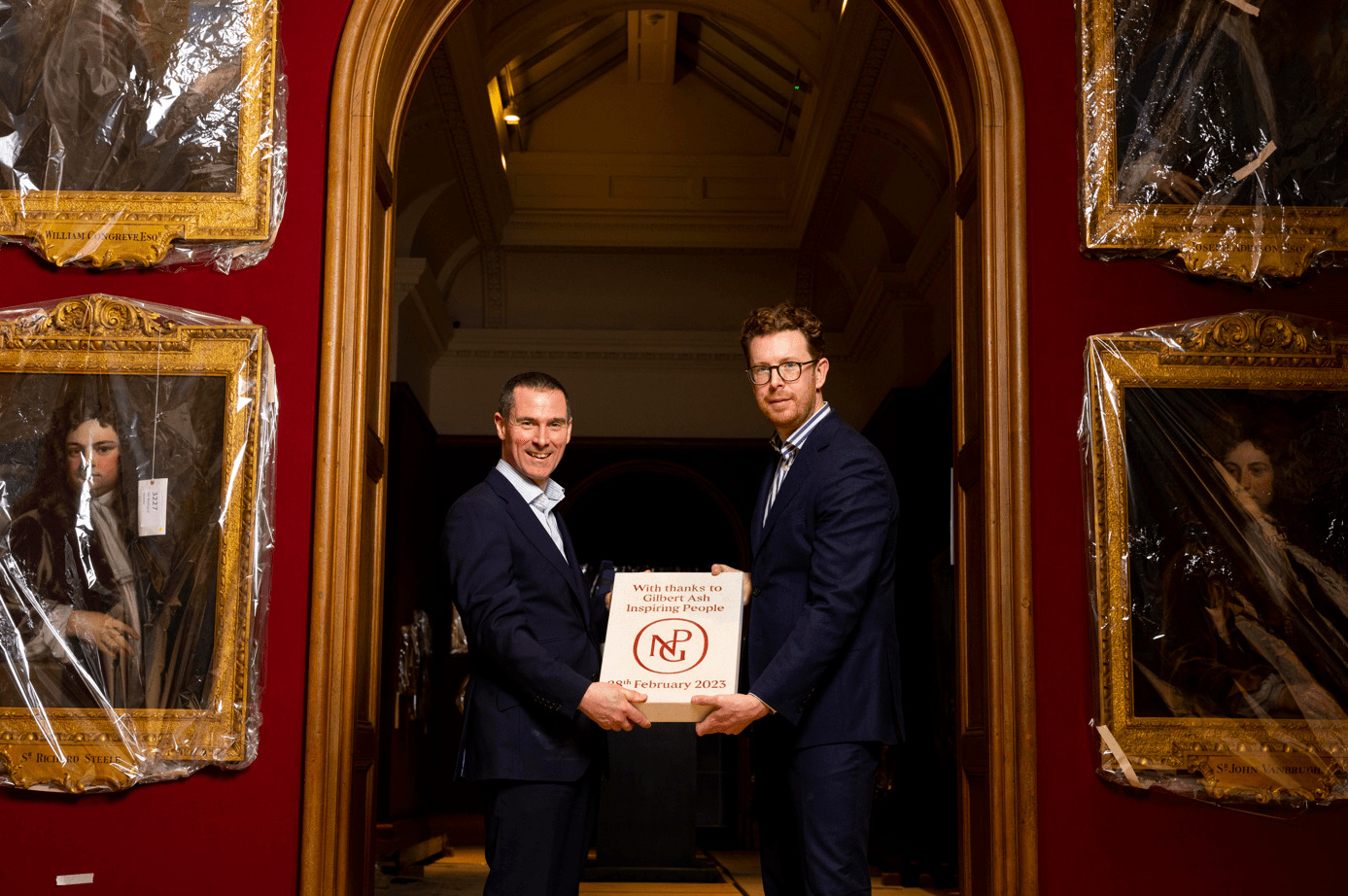 Two men holding what looks like a big white book.
