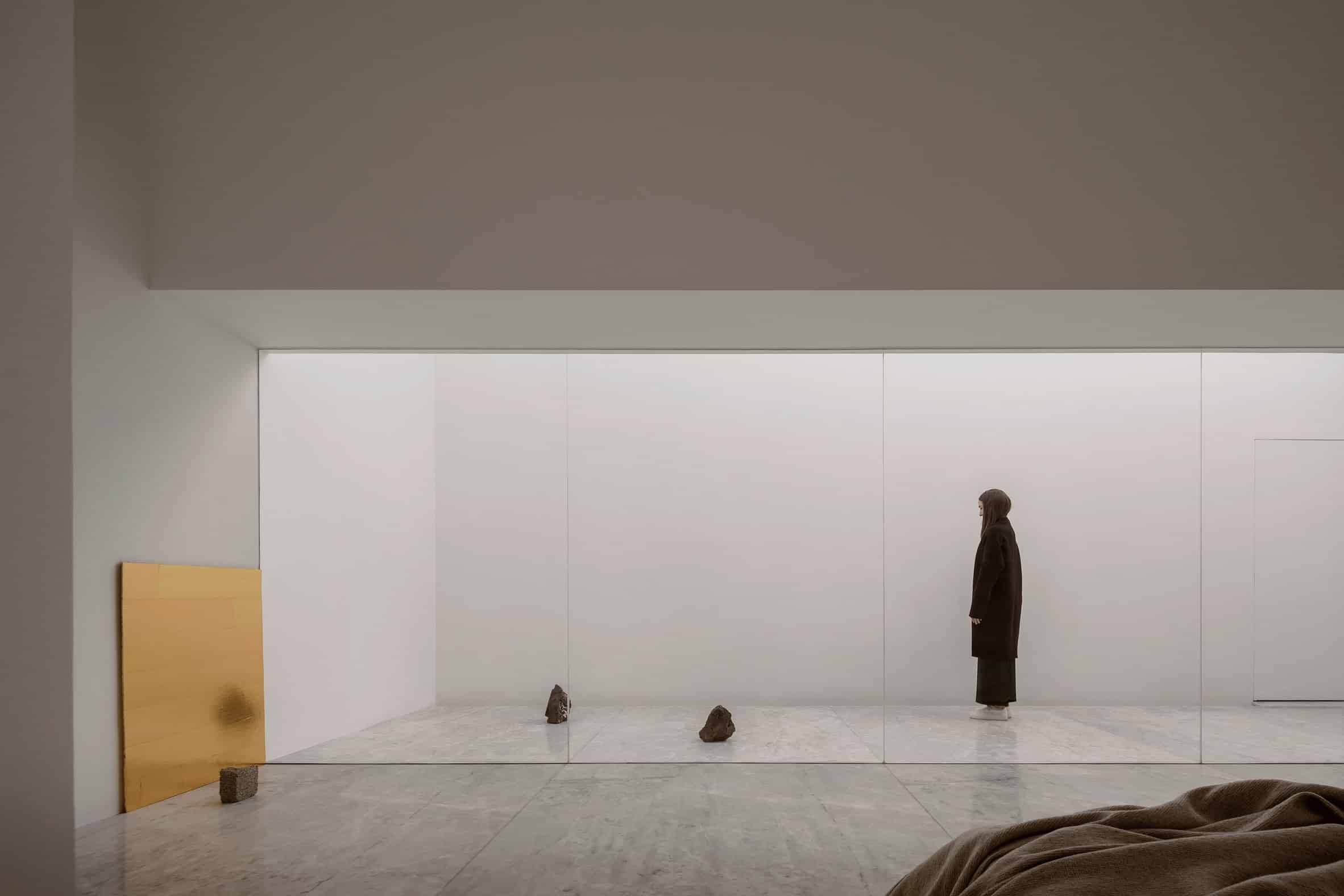 A white bedroom with sliding glass doors opening onto a white courtyard