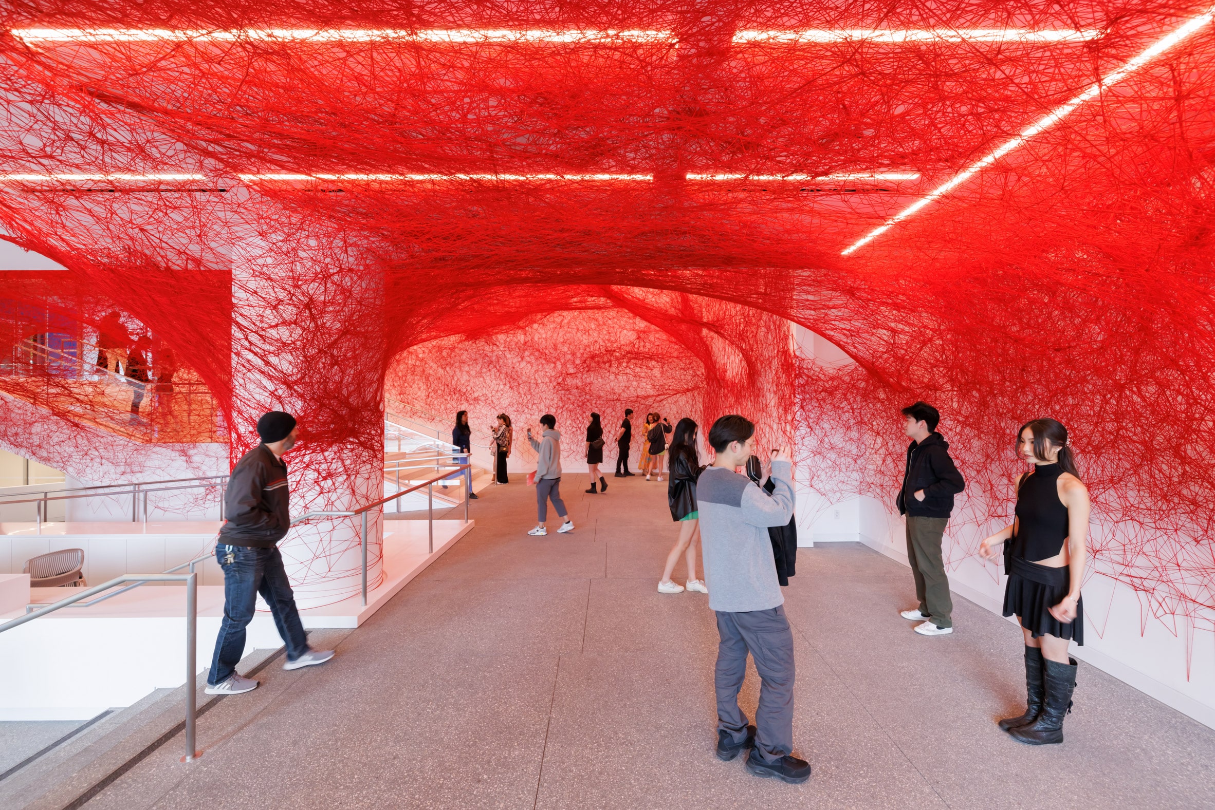 Museum gallery space with white walls covered in red threads