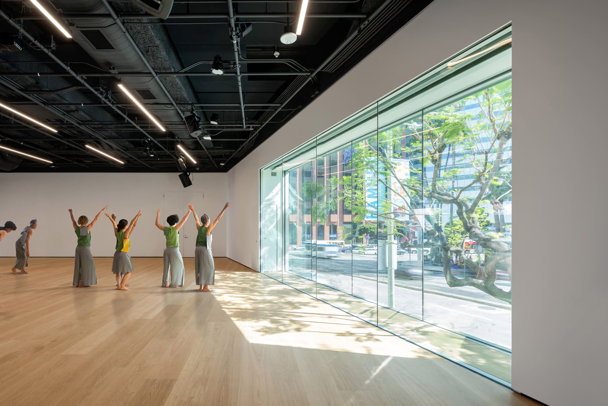 A studio space with white walls, wooden floors and a large window looking out to the street