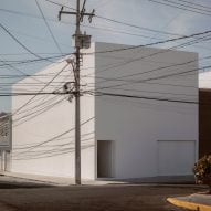 A white cube house on a street corner with telephone poles