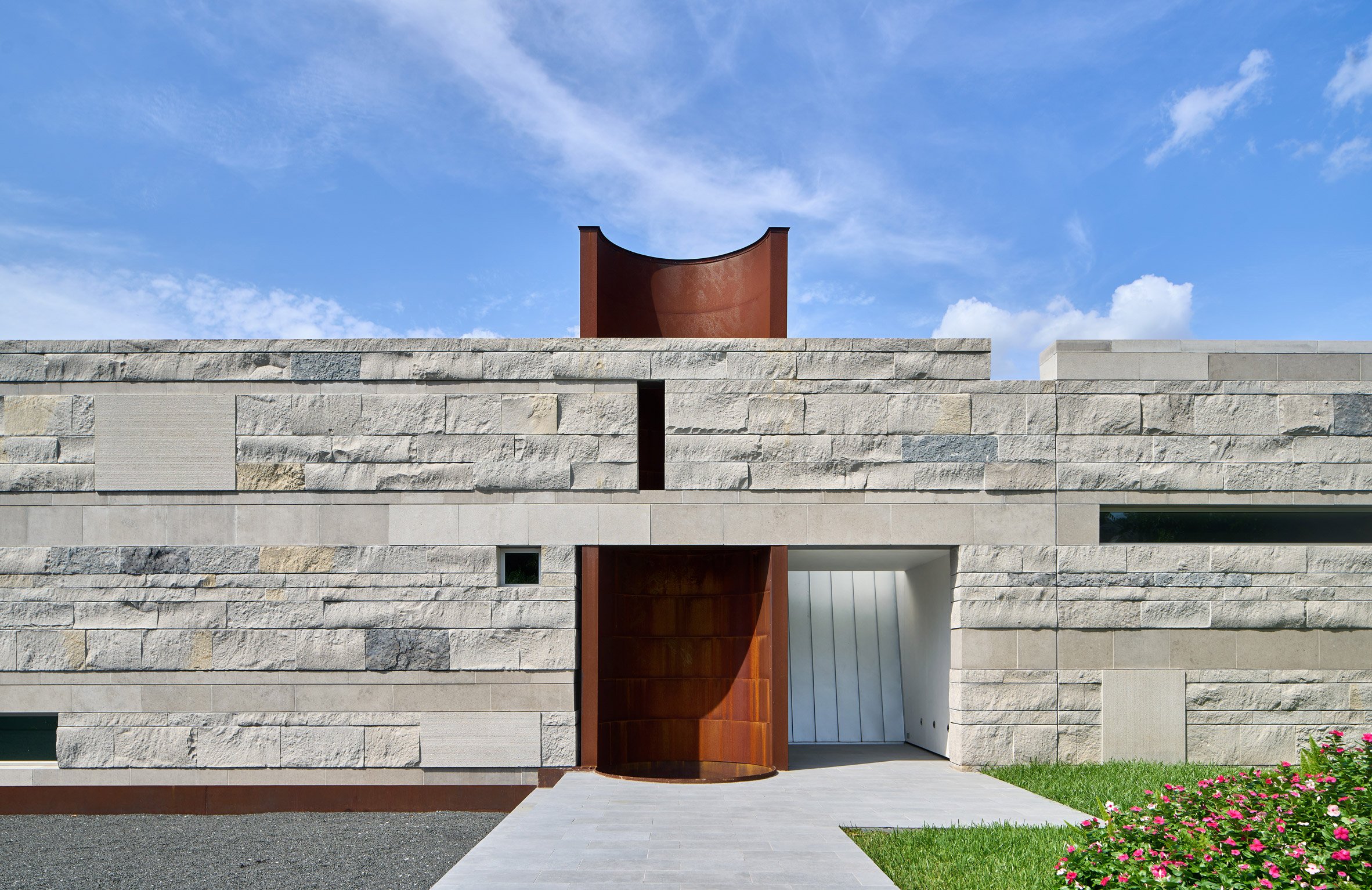 Exterior of a rocky-clad wall with an opening revealing a half-tubular orange tower