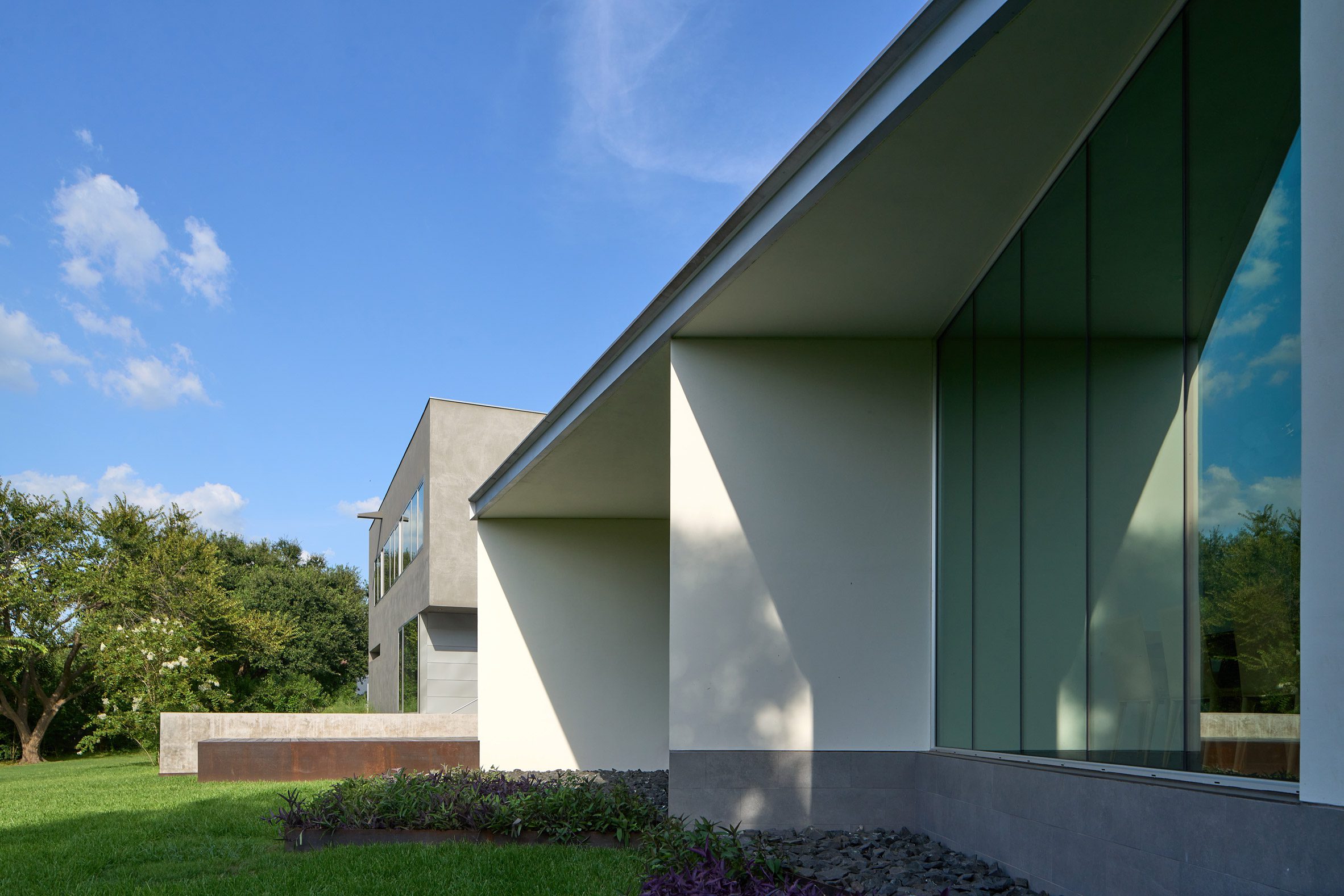 Exterior of a home with floor-to-ceiling windows separated by white perpendicular walls