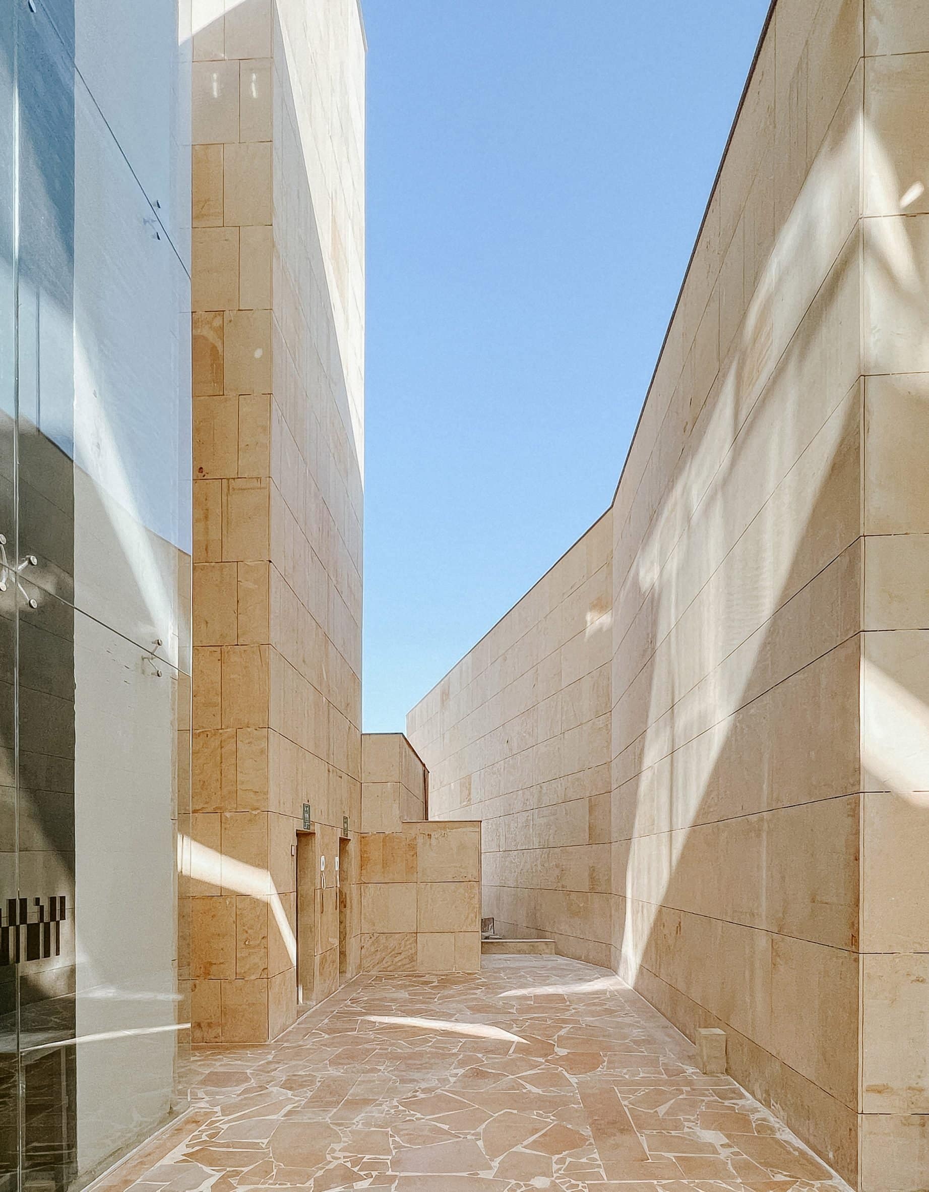 An outdoor walkway with tall cream-coloured stone walls