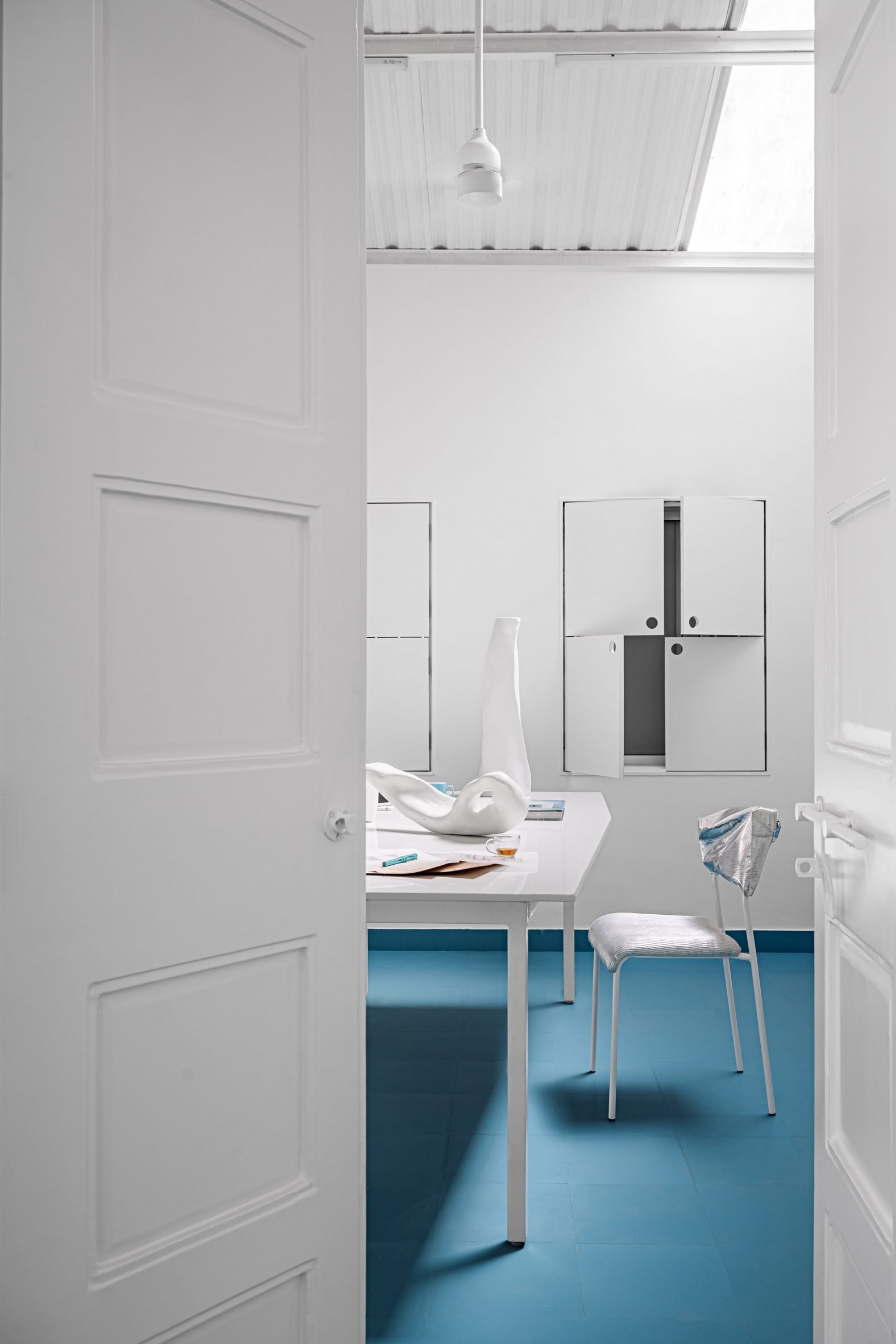 Inside The Act of Quad's studio space, with white furniture and a blue floor