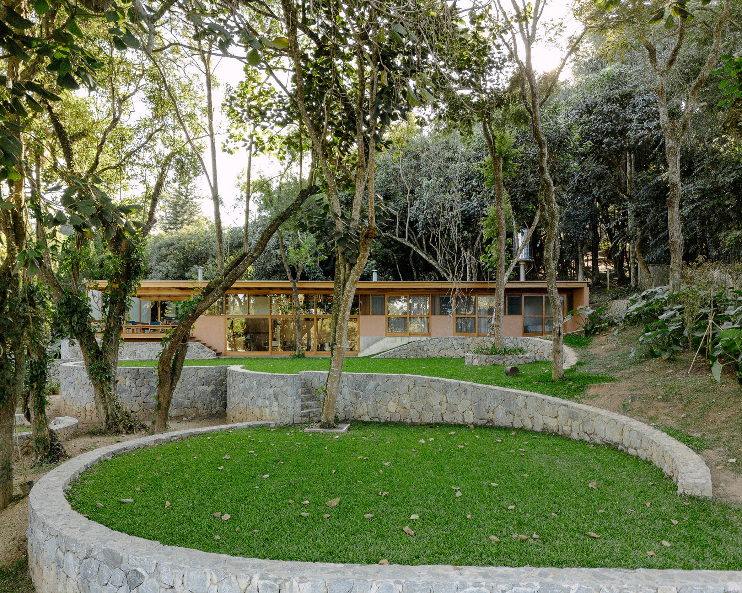 Curving stone walls around rectilinear Brazilian home