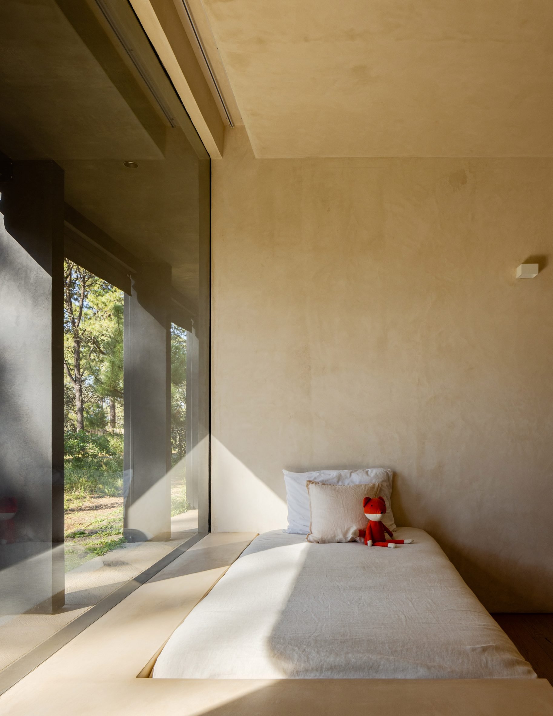 A bed in a room with a large window and light wood paneled walls