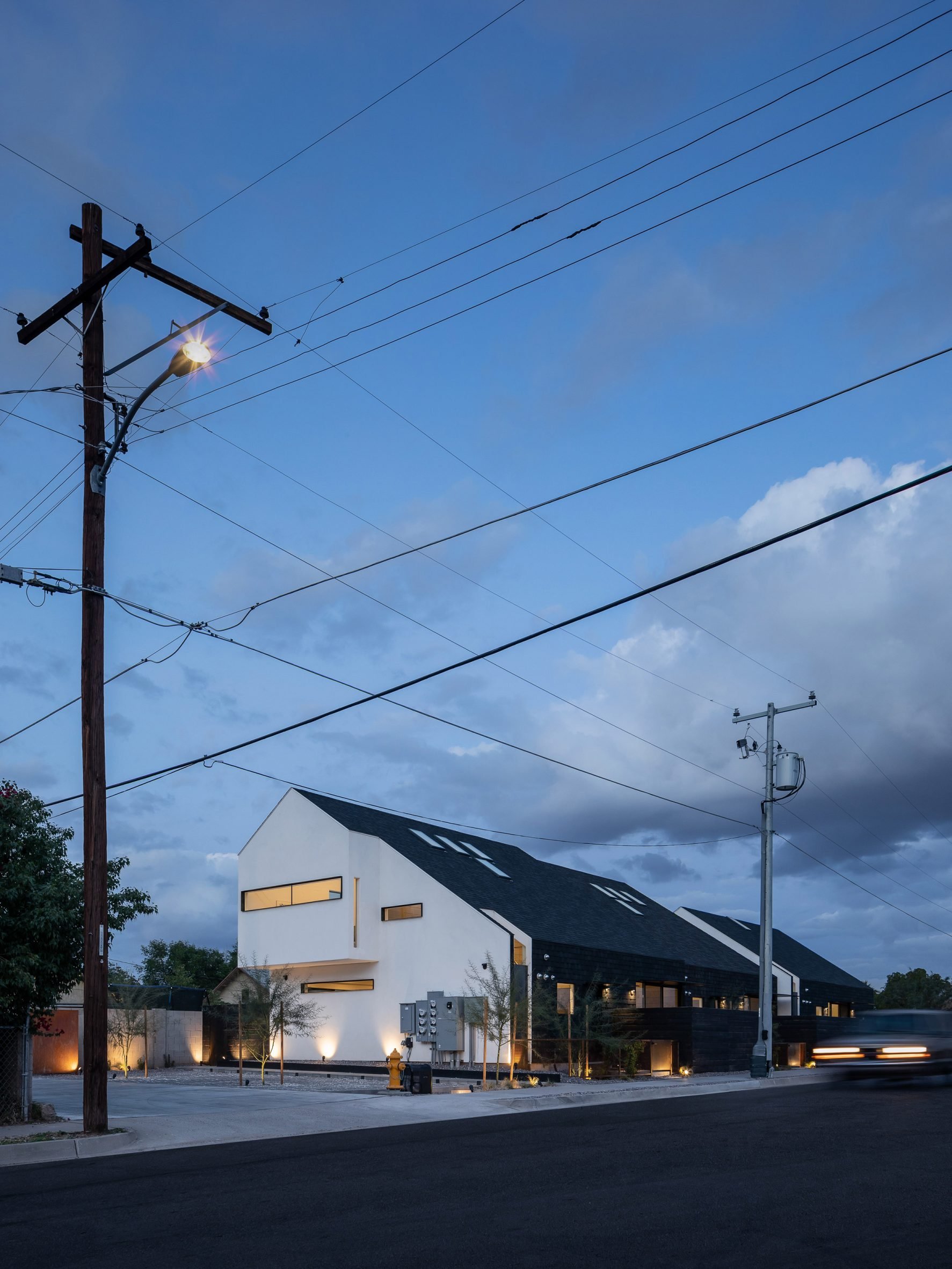 Pitched roof house clad in asphalt shingles with extruded upper level and white gable end