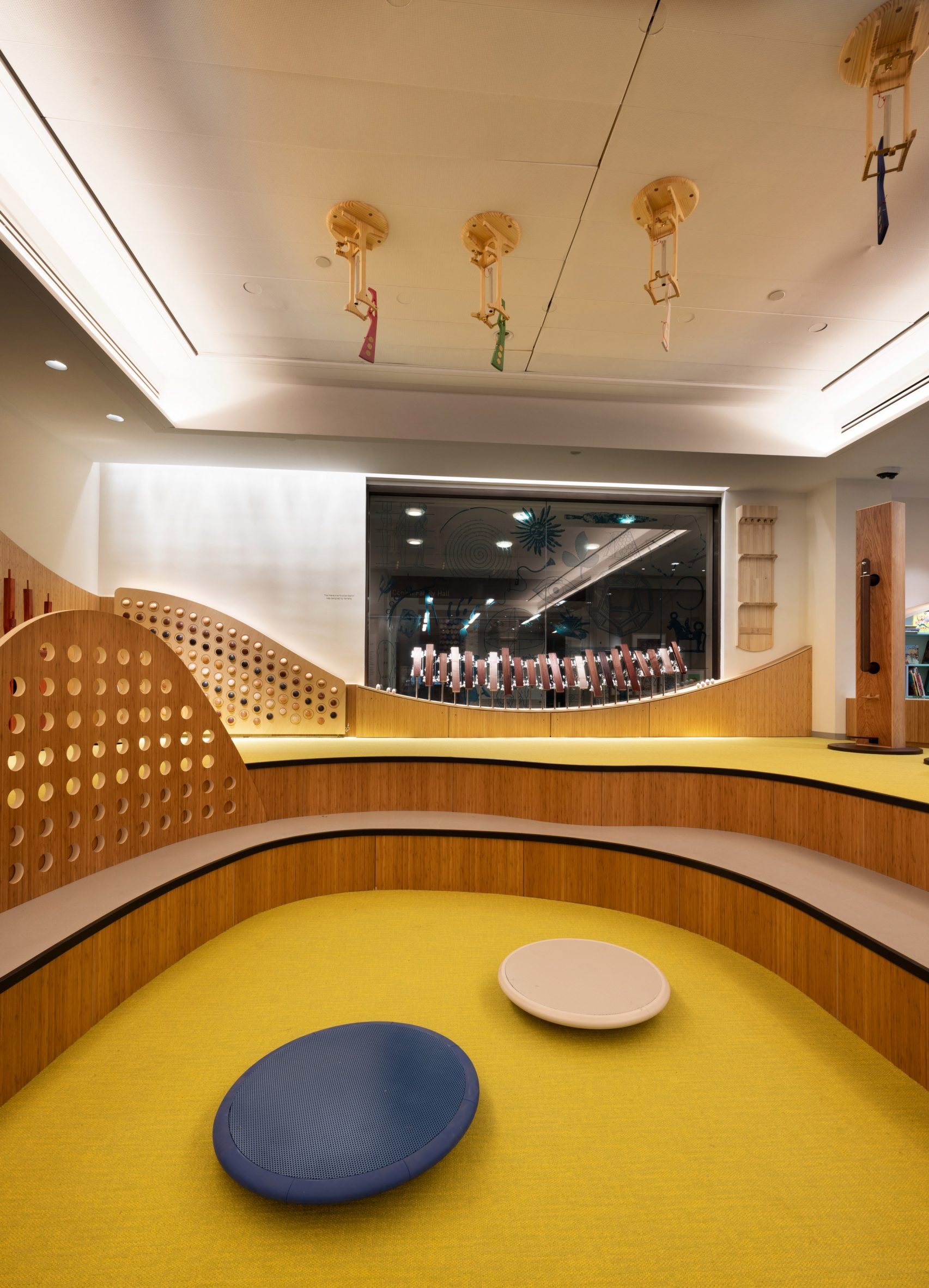 Curved seating around a yellow carpet with balancing furniture