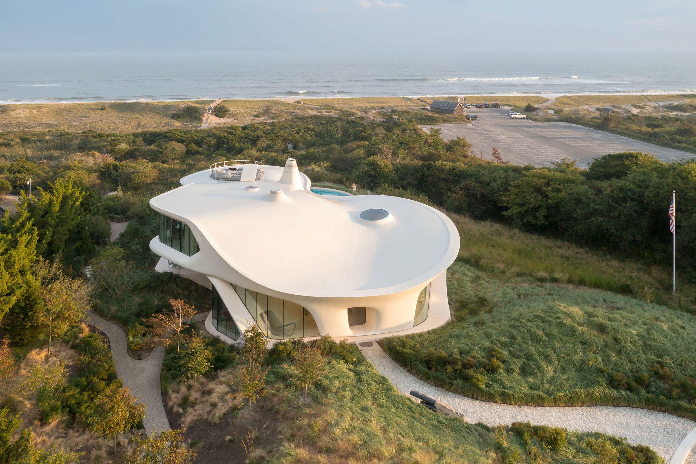 Modern home with white sloping roof and beach in the background