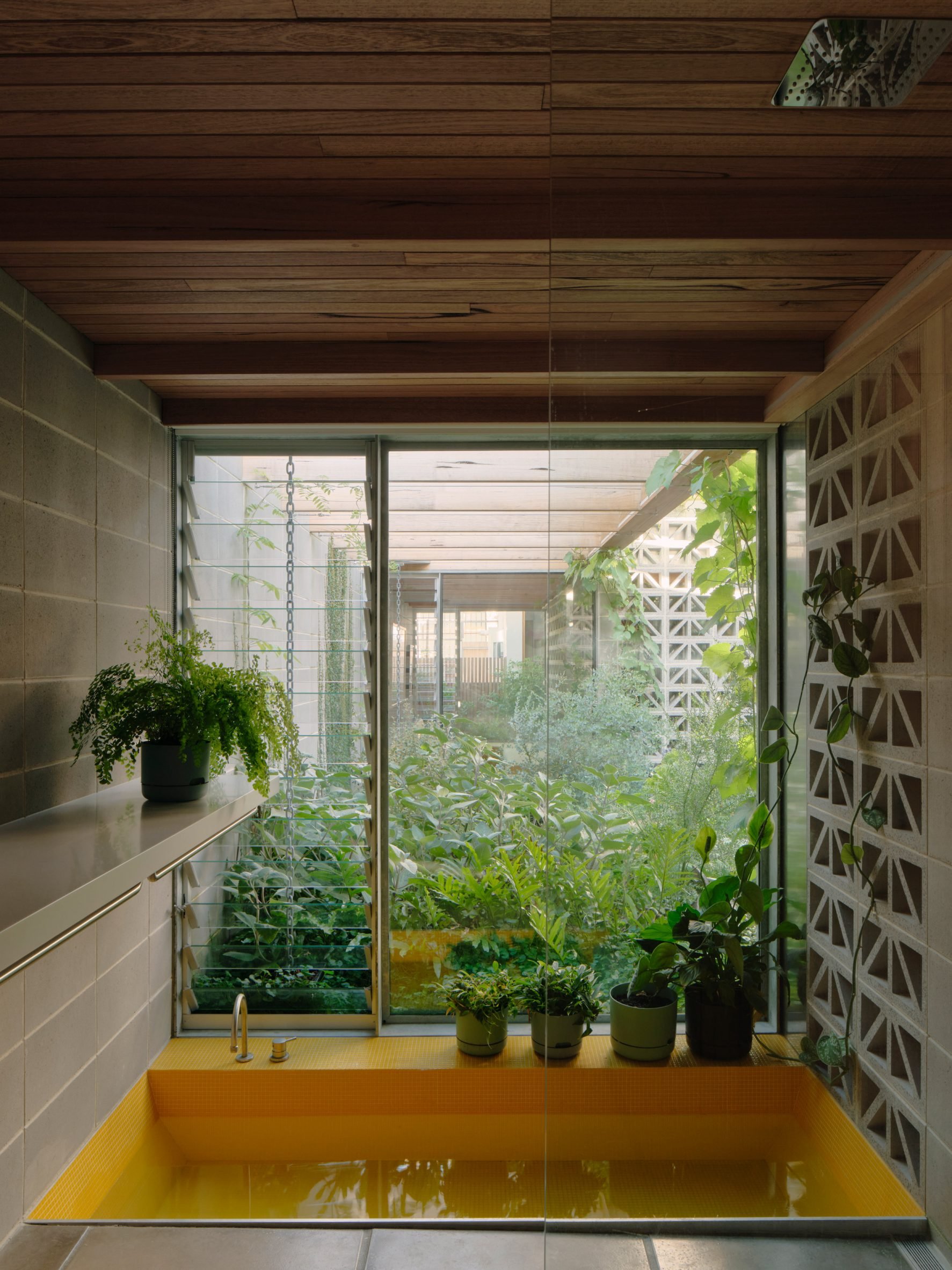Yellow bath by a window with perforated breeze block walls