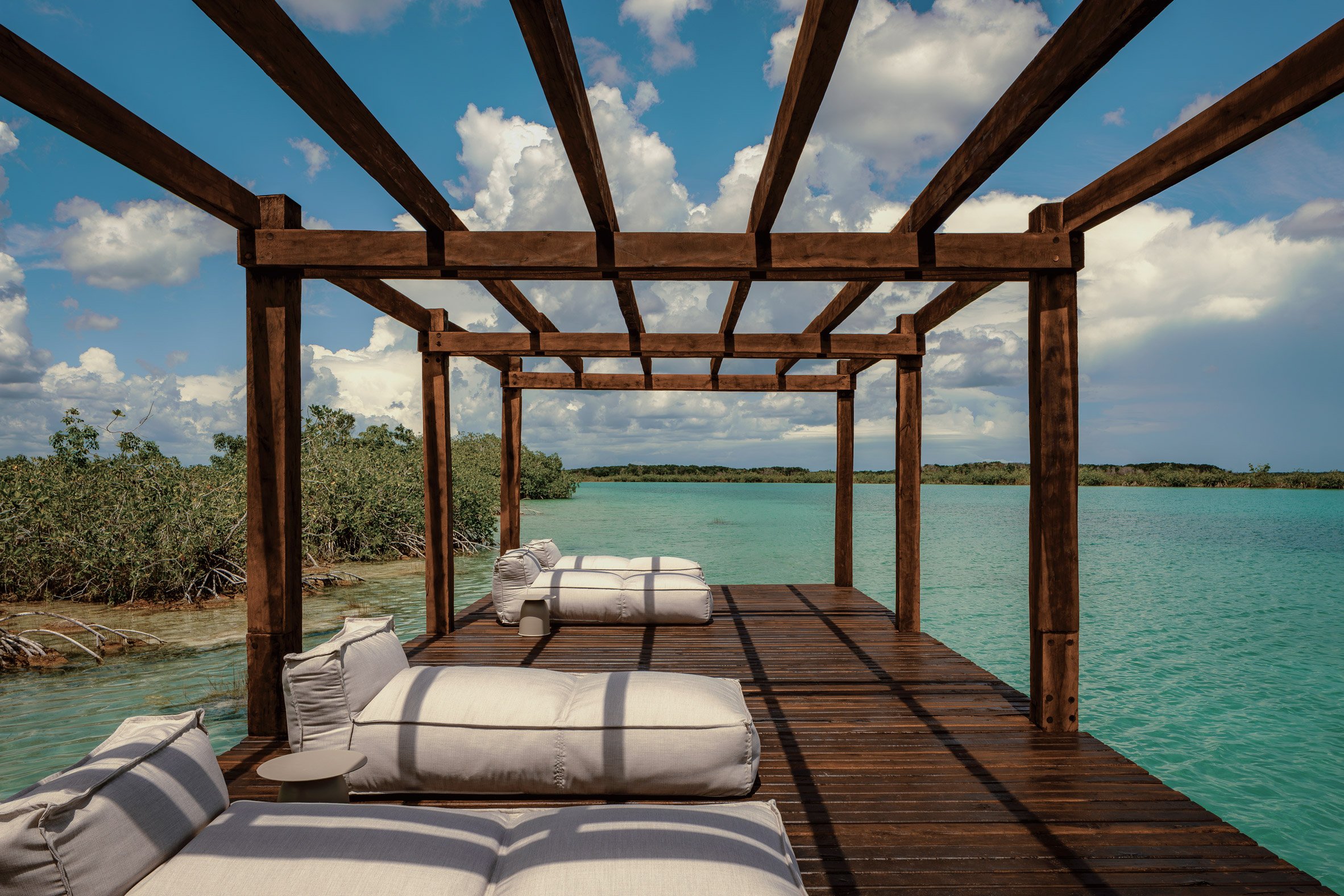 a long dock made of dark wood with lounge cushions