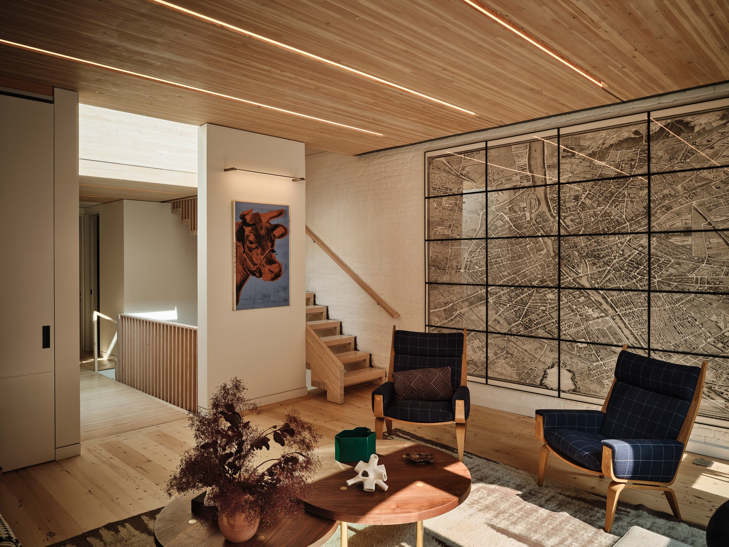 A living room with a large map and blue armchairs
