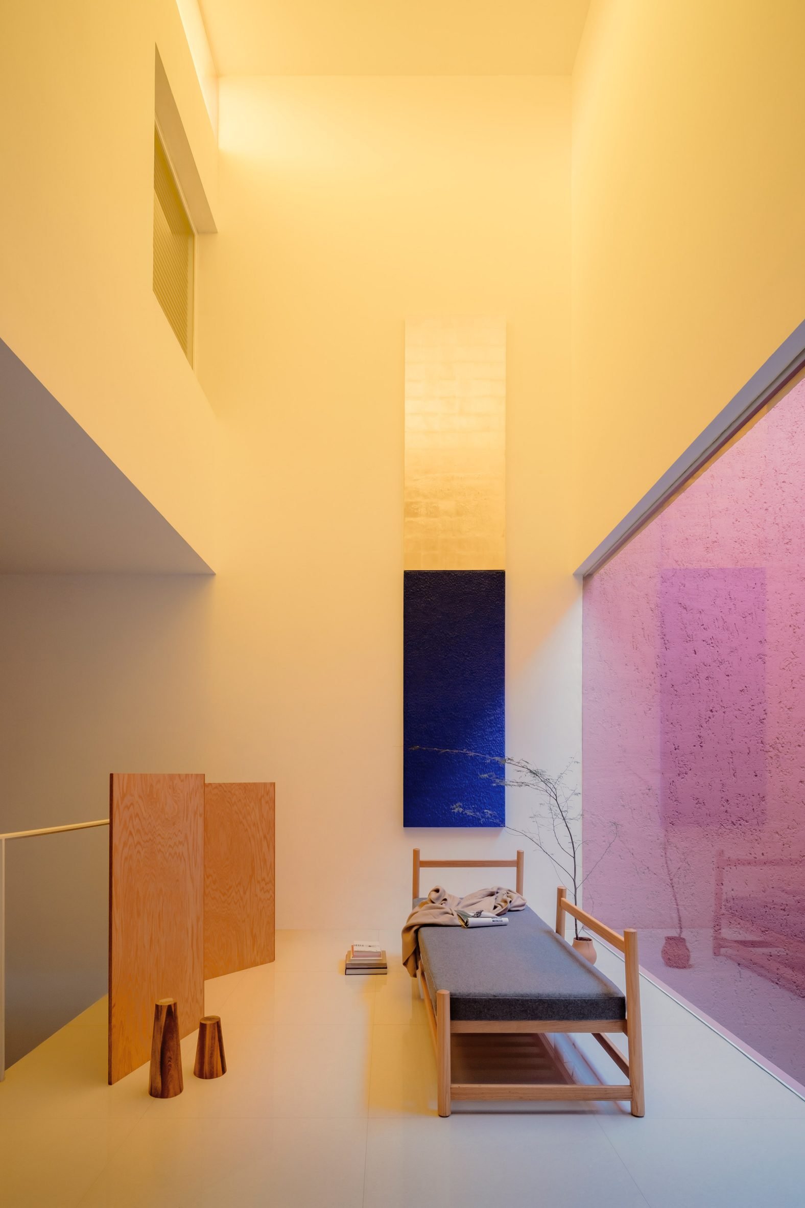 Double-height living space with yellow light from a clerestory window above