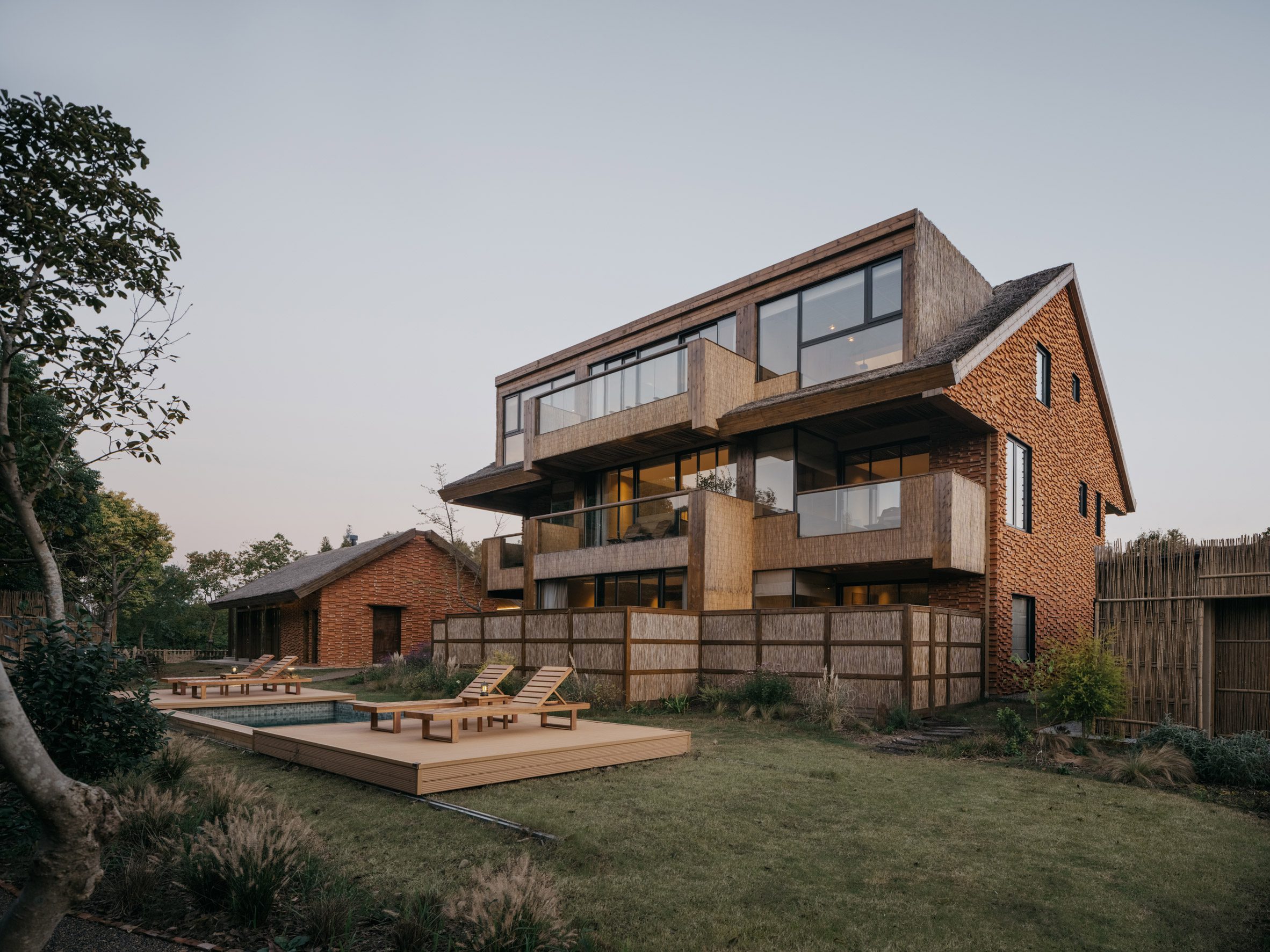 Two buildings clad in recycled bricks and thatched roofs