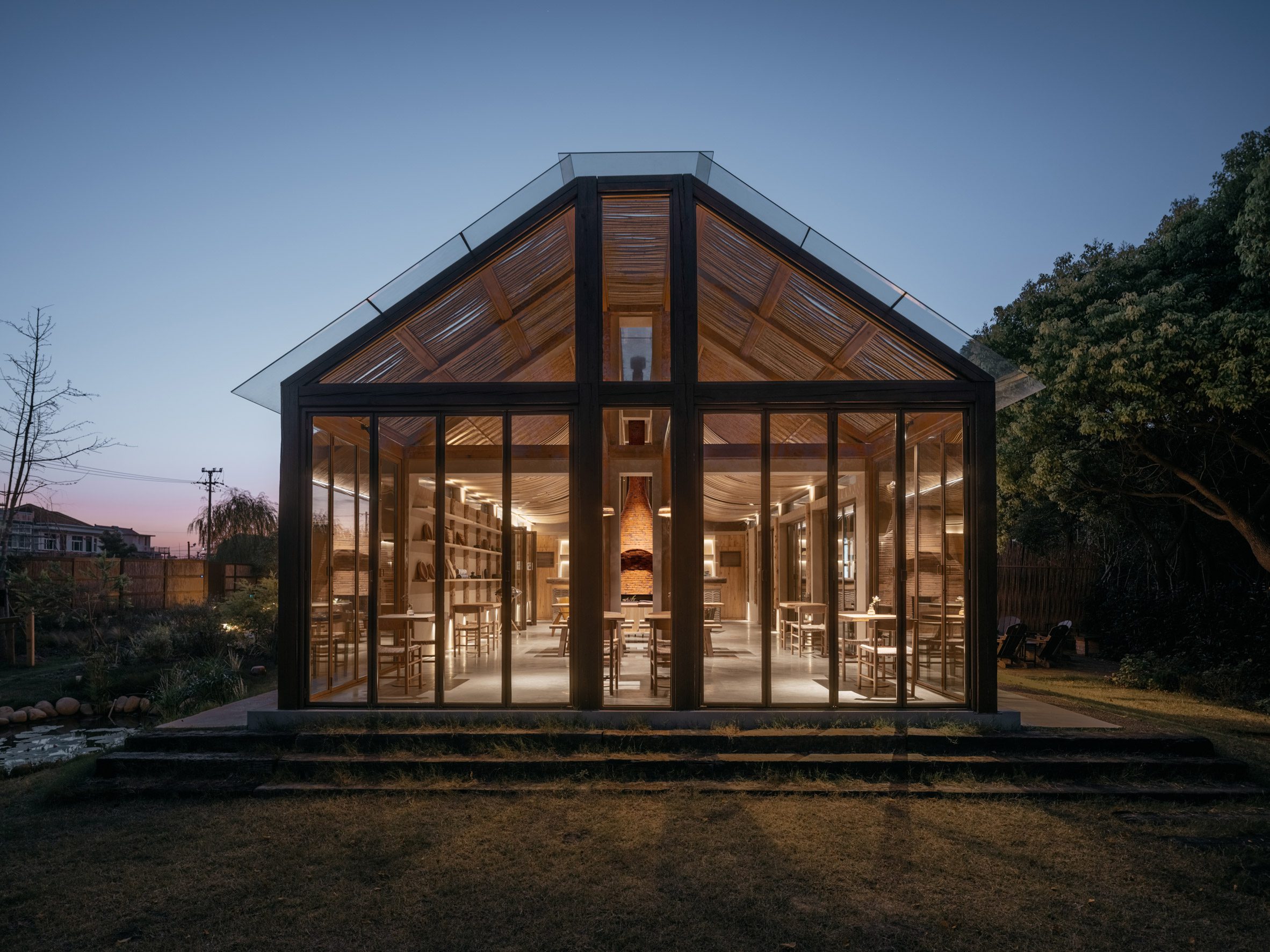 Gabled structure with glass walls glowing at night