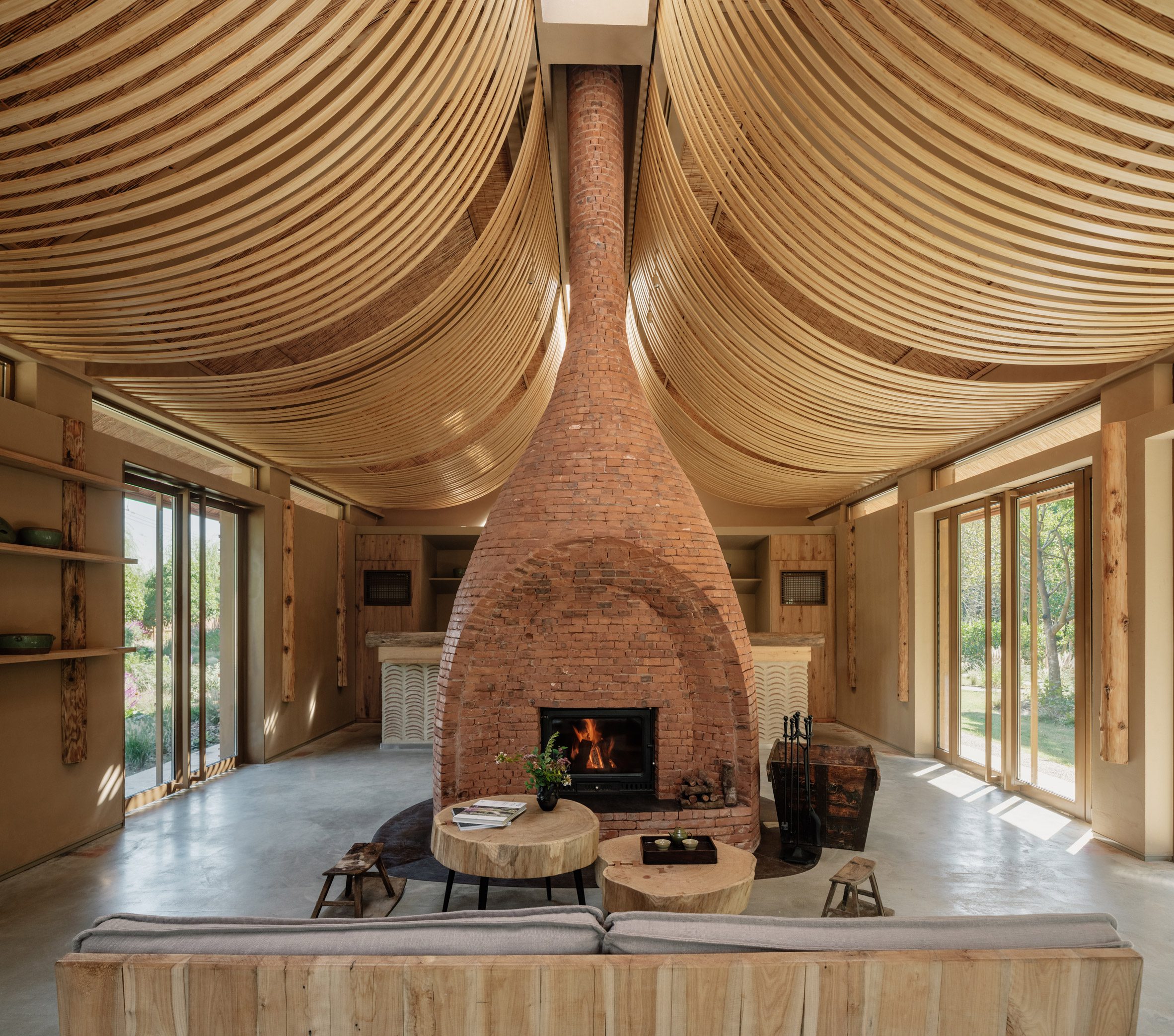 Strips of wood curve from the ceiling, while a central brick fireplace divides the open space