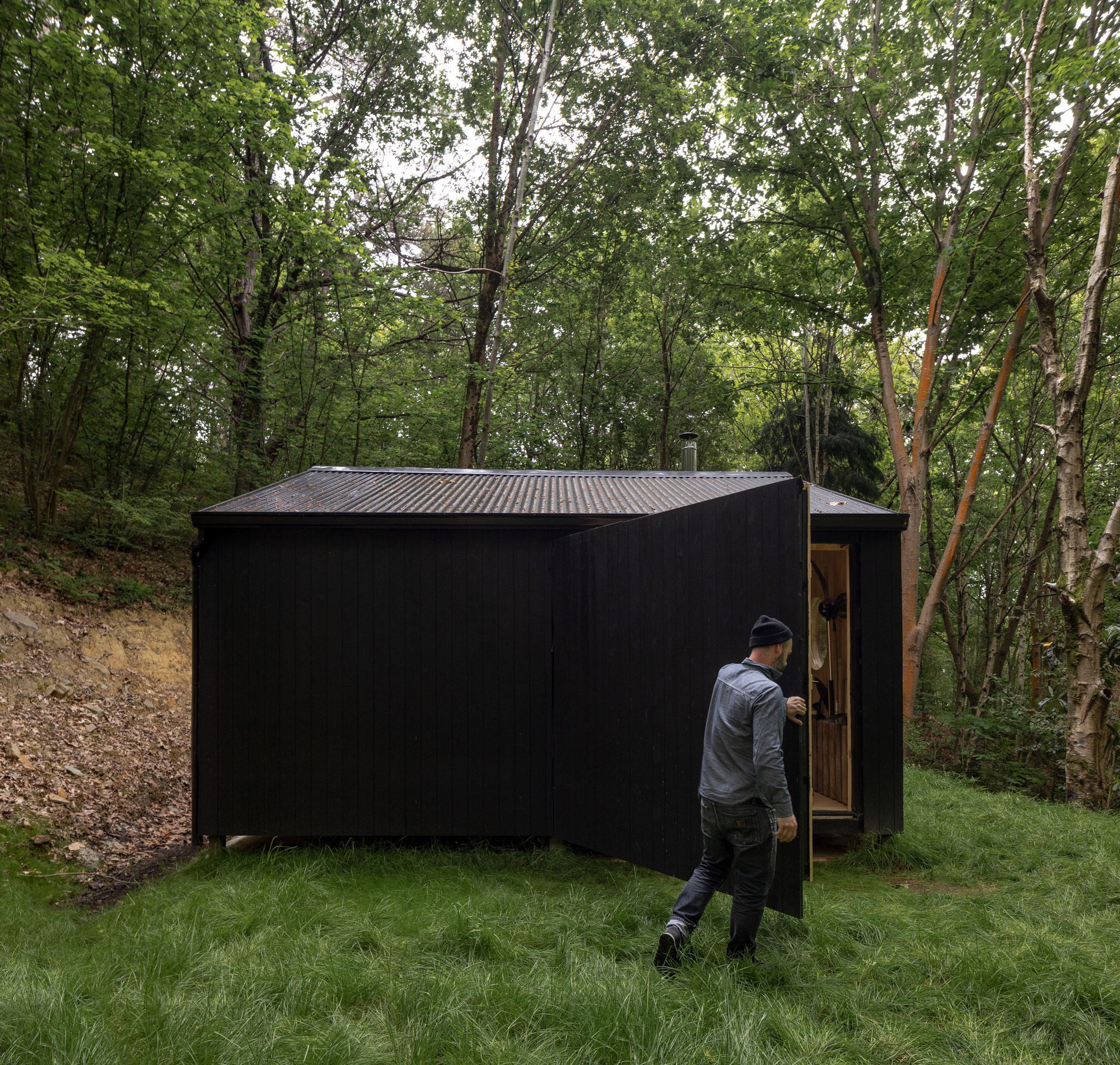 Man closing door of black woodland cabin