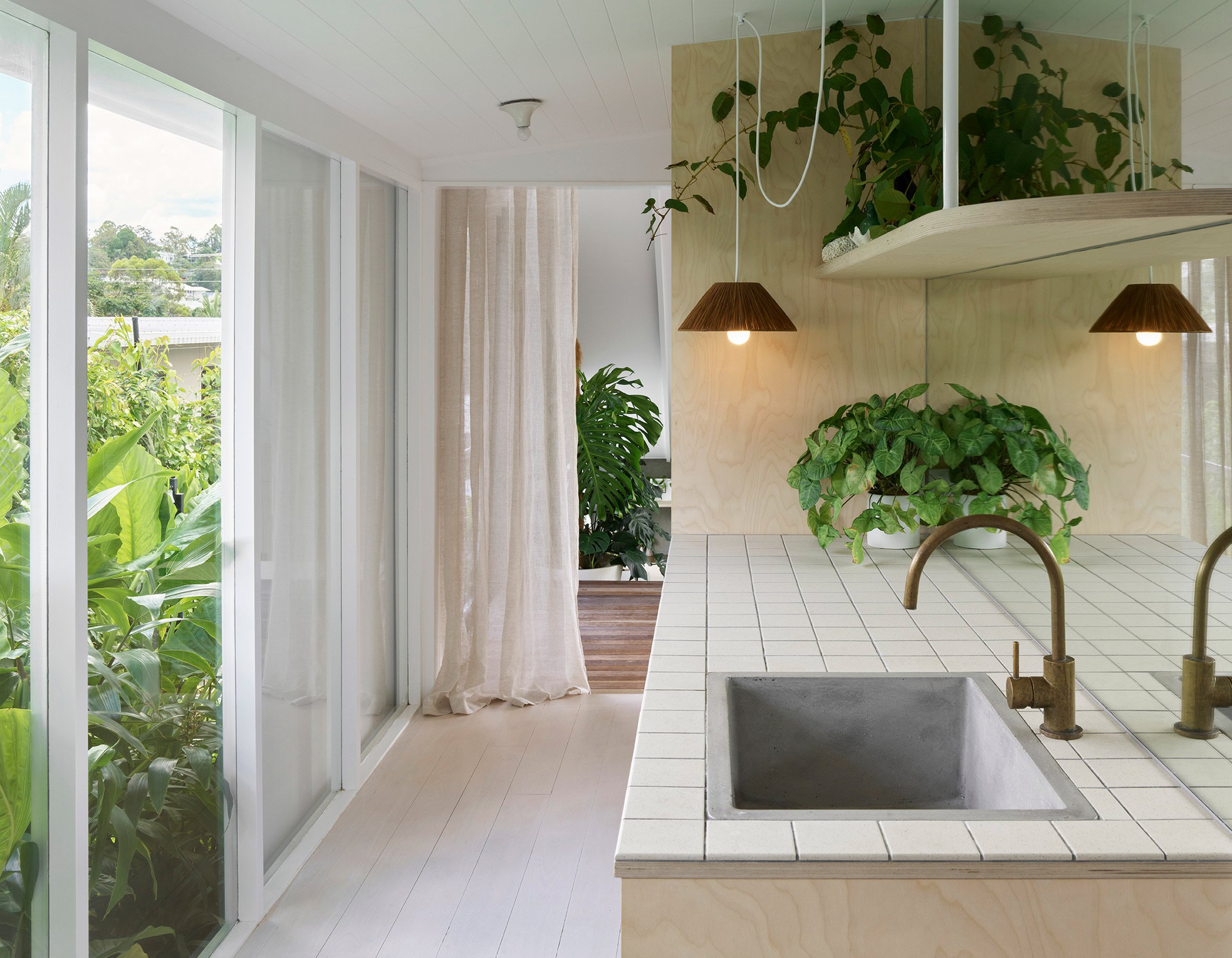White kitchen in Cascade House by John Ellway with glazed doors leading to a garden