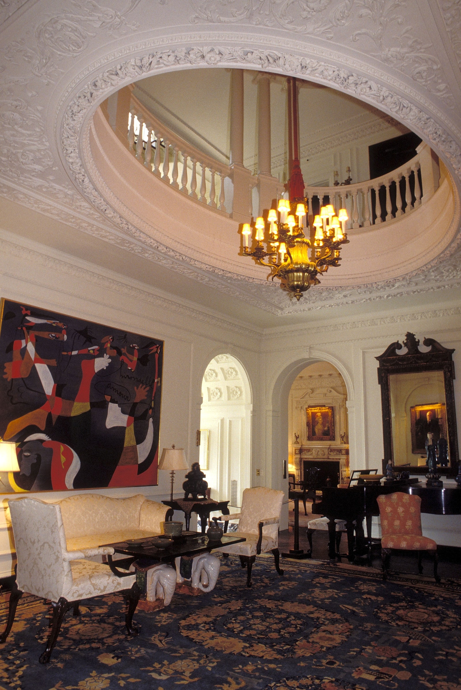 Kykuit Rockefeller mansion with circular ceiling cutout through which a chandelier hangs large artwork on left wall...