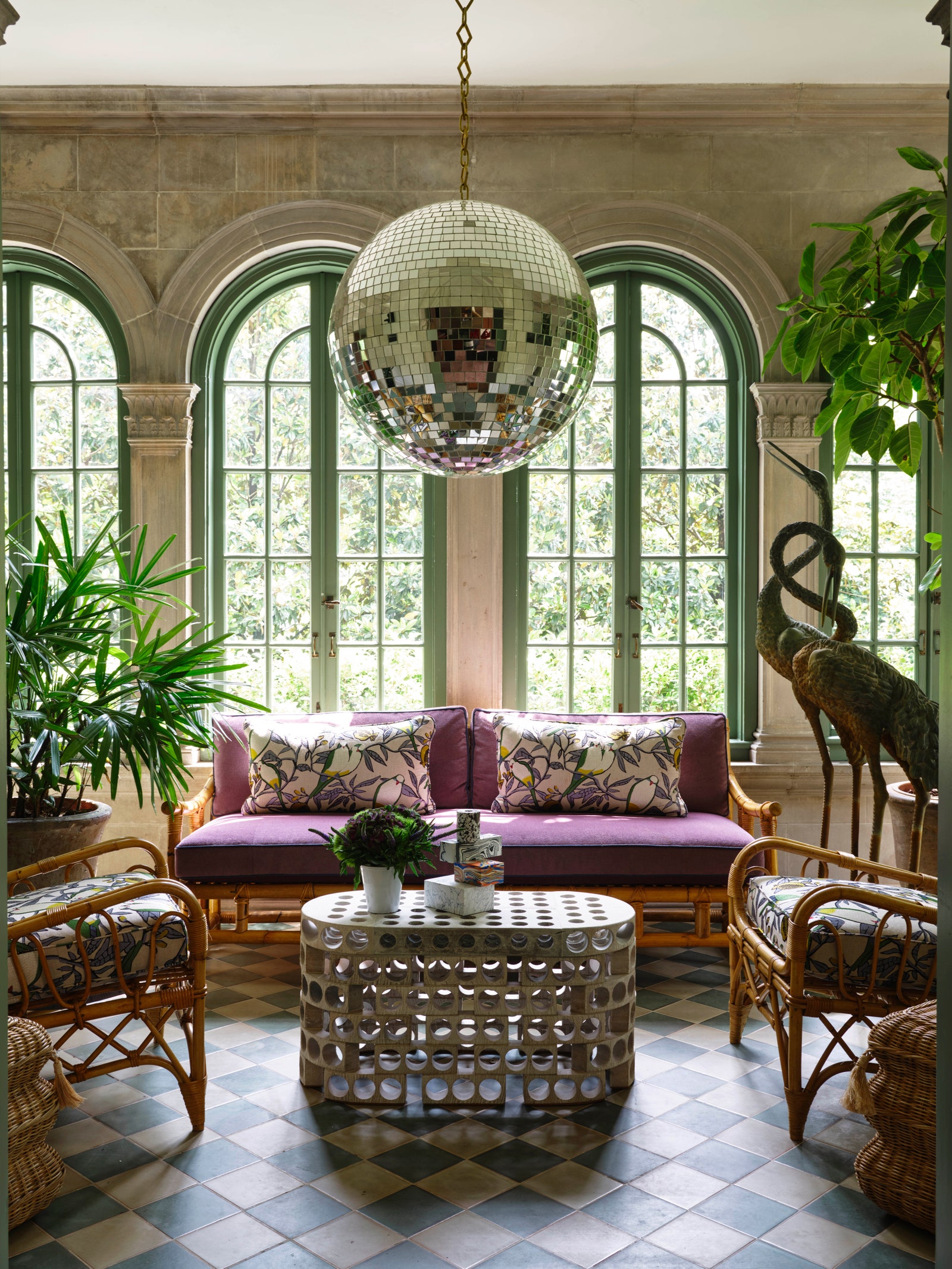 rattan furniture in a sunlit sunroom with a large discoball suspended overhead