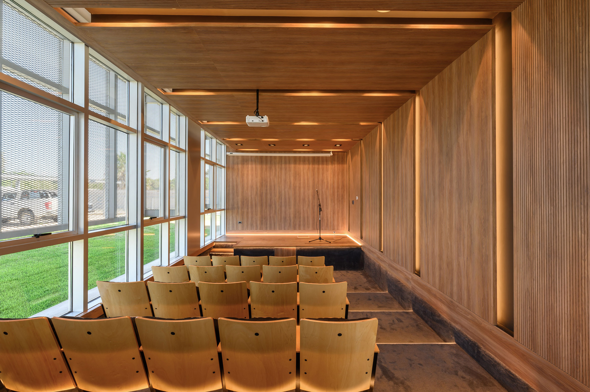 A small wood paneled room with theatre seating and large windows