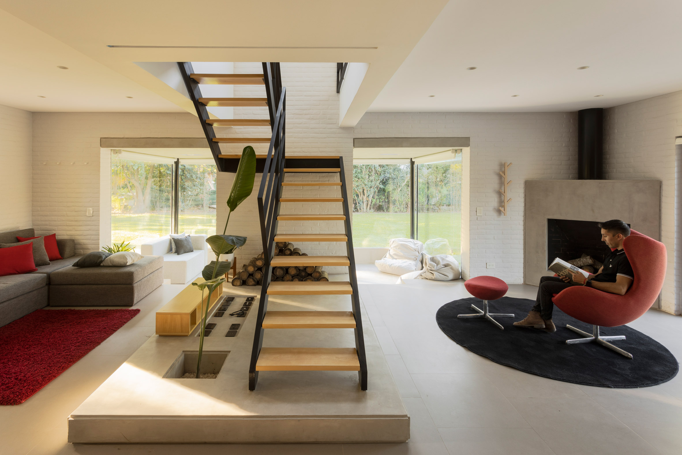a liviing room with a red chair and exposed staircase
