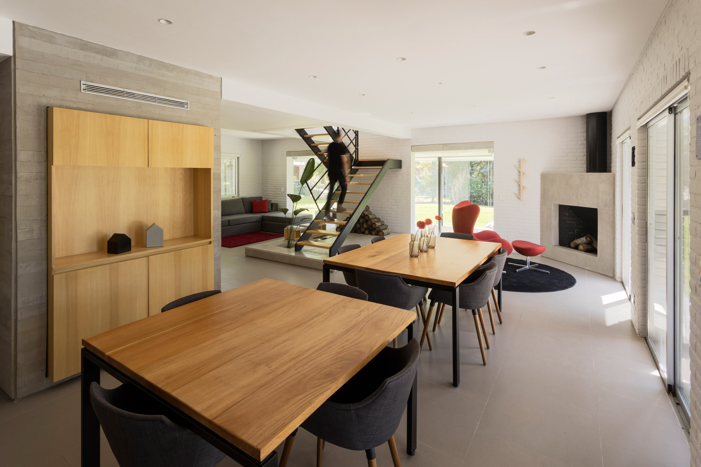 a dining area with wooden tables and a staircase at its centrea