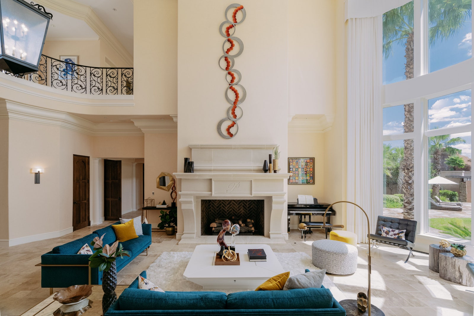 tall ceilings white walls tall windows to left white fireplace mantel two blue sofas white cocktail table