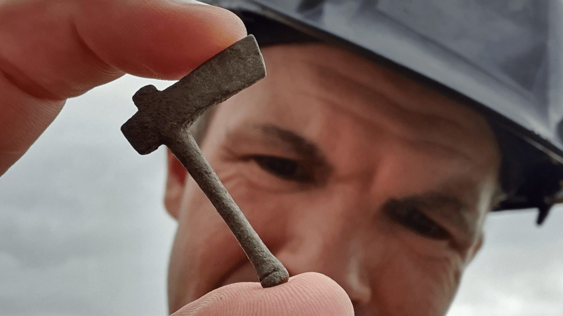 A man in a hard helmet holding a miniature axe.