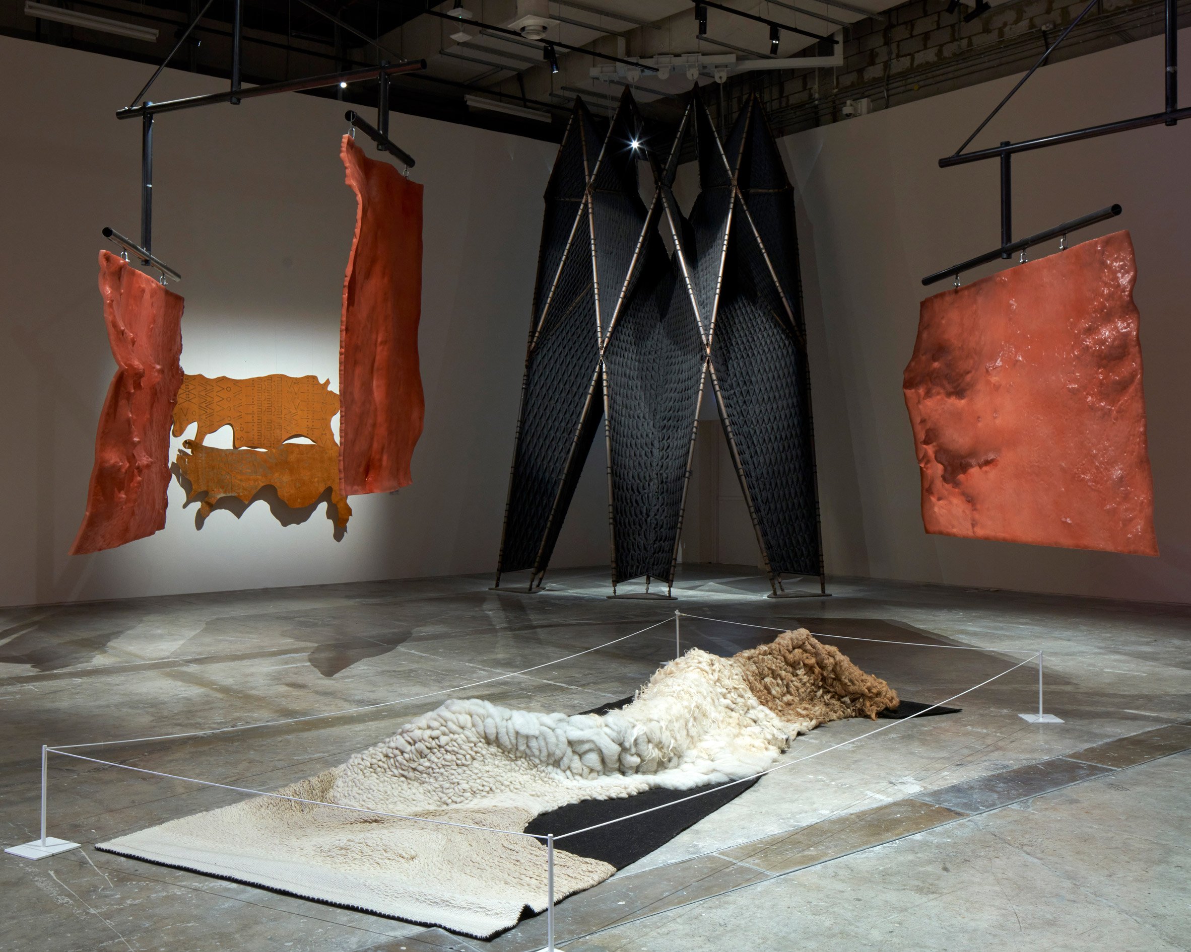 An exhibition space with various artworks on the floor and walls