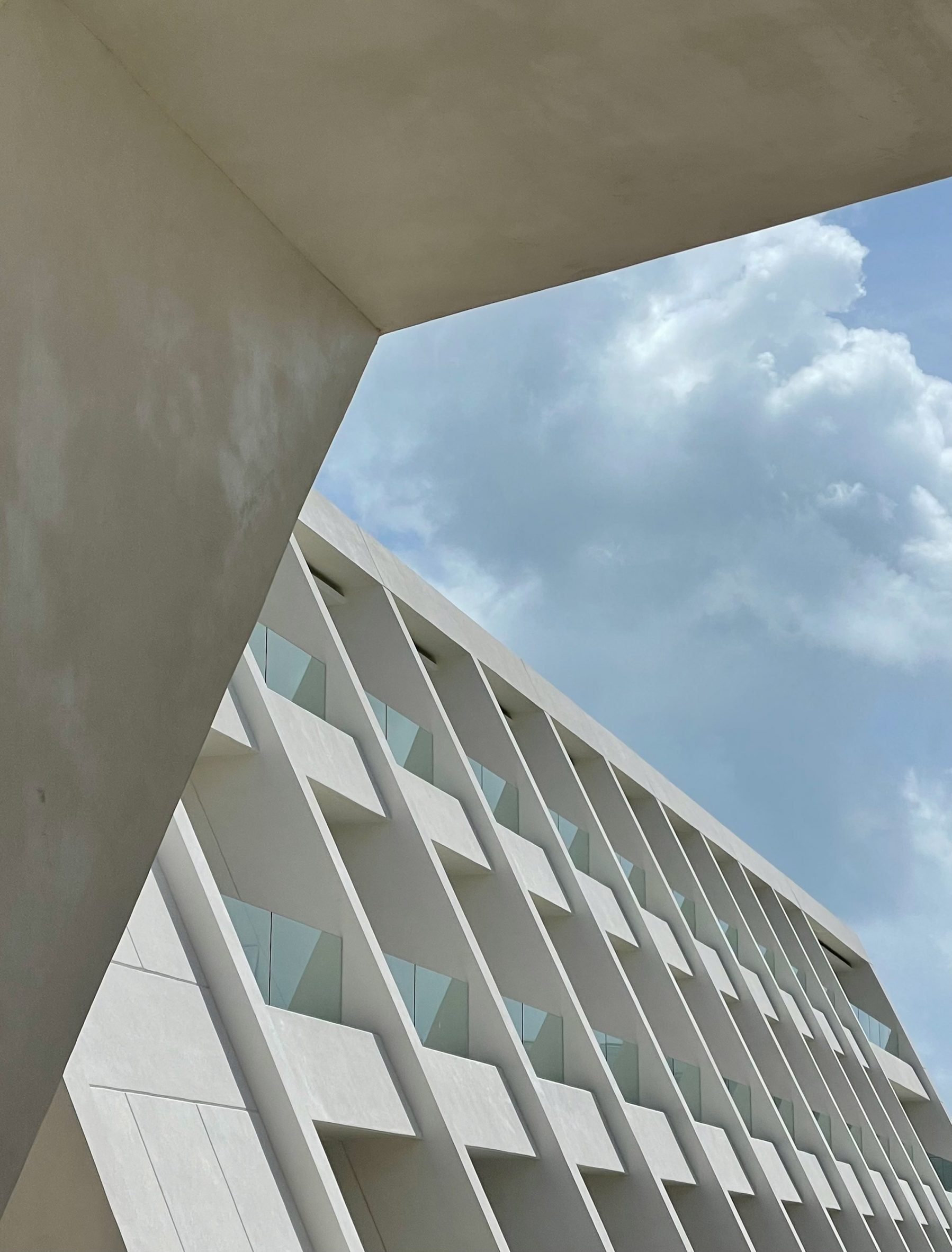 White angled building with three storeys of balconies