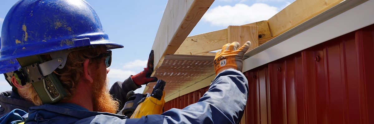 Construction worker installing metal soffit 
