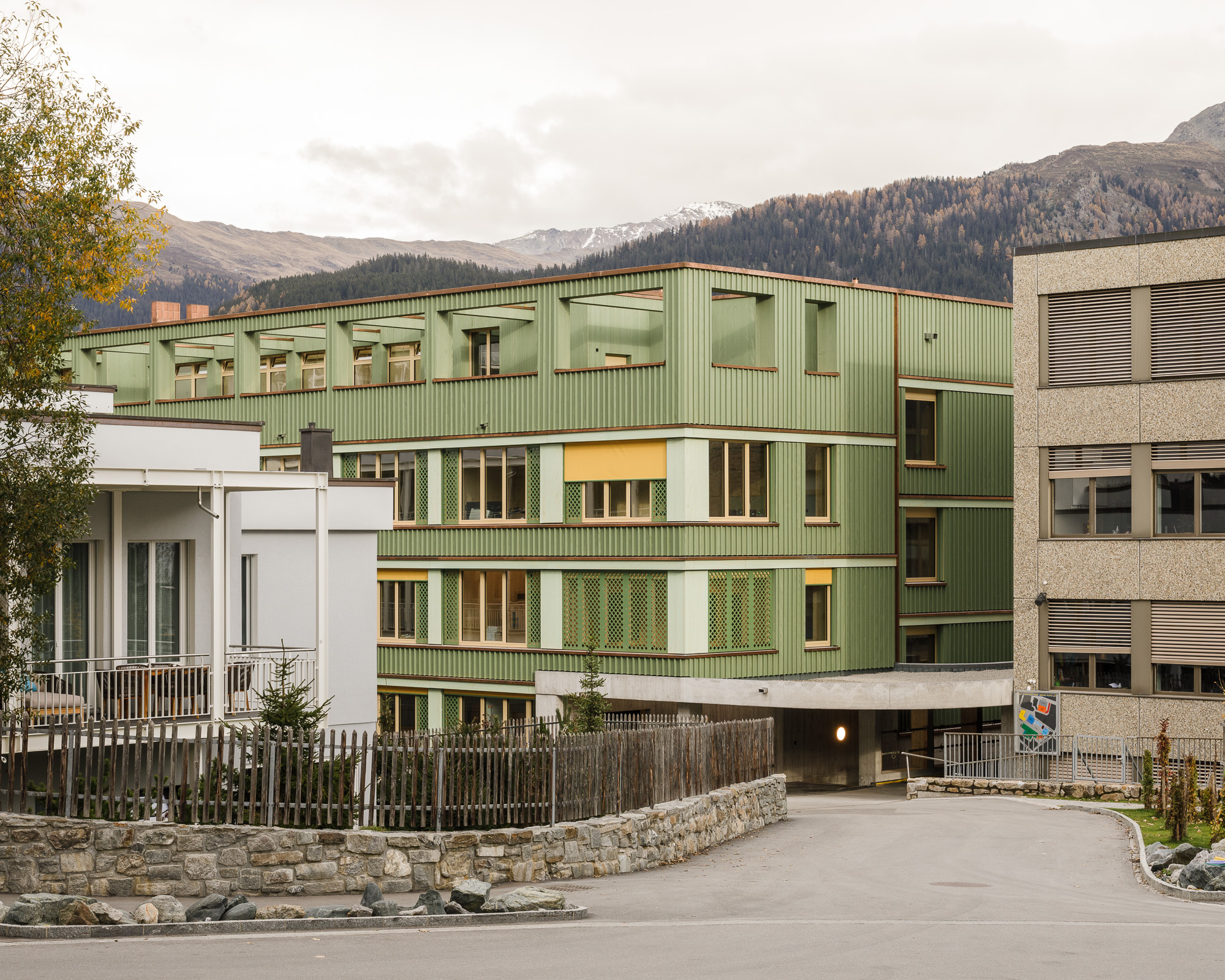 Adaptive reuse of 1960s school building with new timber construction in the Swiss Alps.