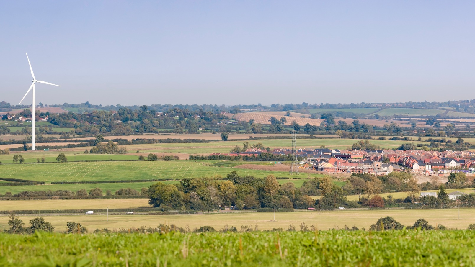 A field with a wind turbine and new build homes